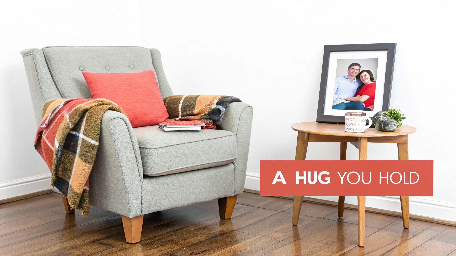 A cozy grey armchair with a plaid blanket and a side table featuring a framed photo of a smiling couple.
