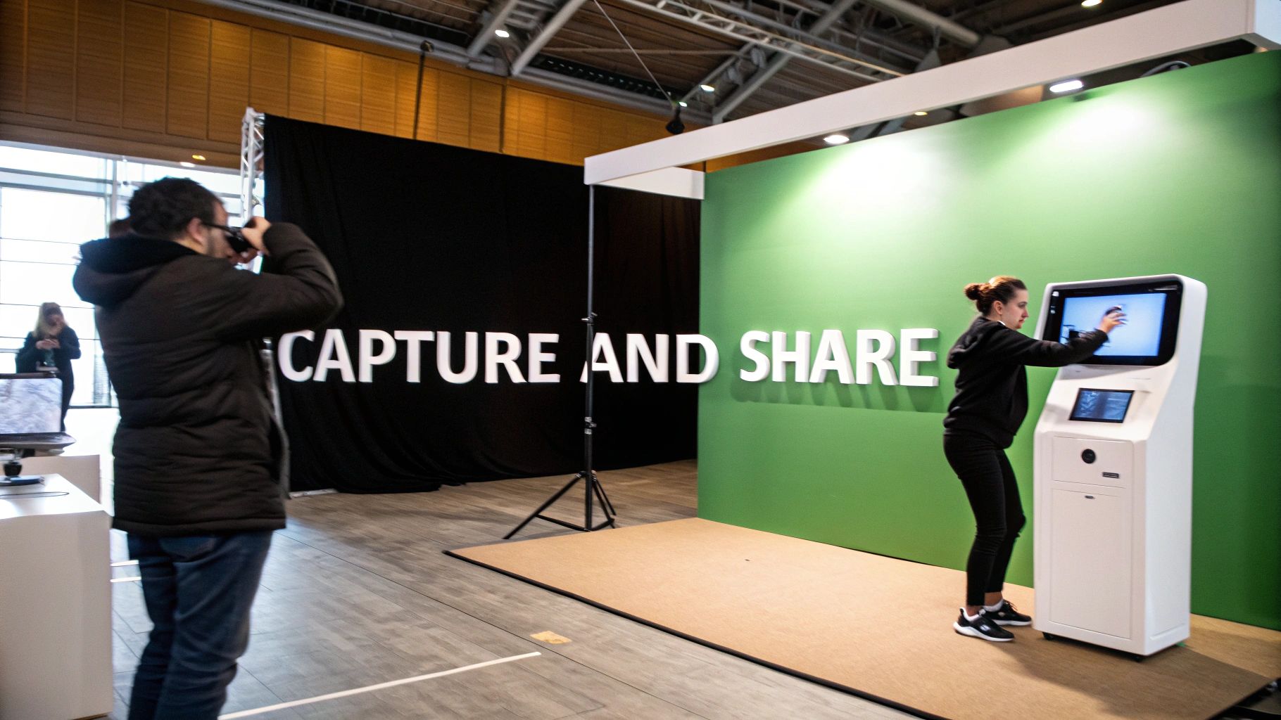 Attendees interacting with a photo booth and digital screen at a 'CAPTURE AND SHARE' exhibition stand.