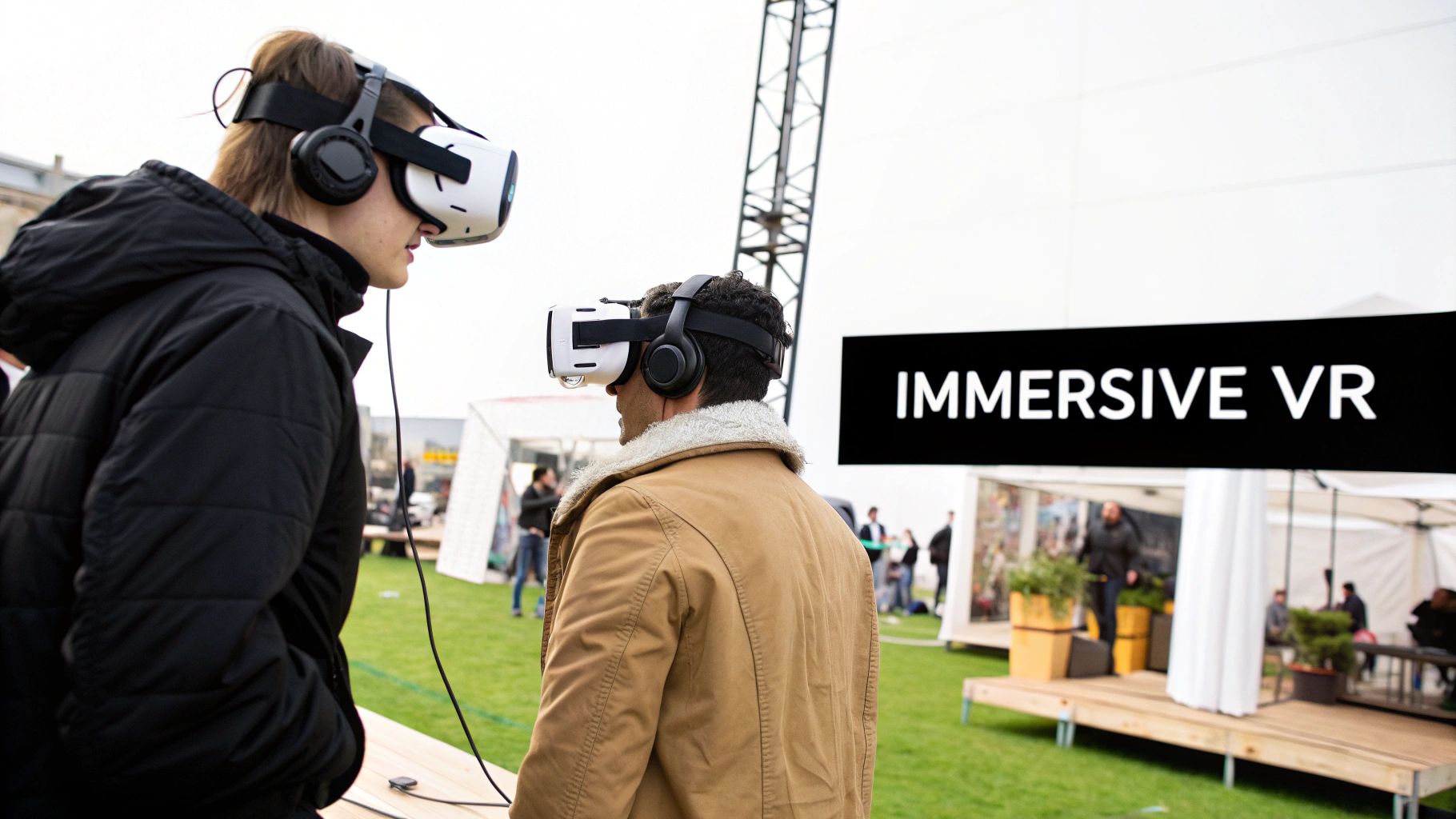 Two people wearing VR headsets and headphones experience immersive virtual reality at an outdoor event.
