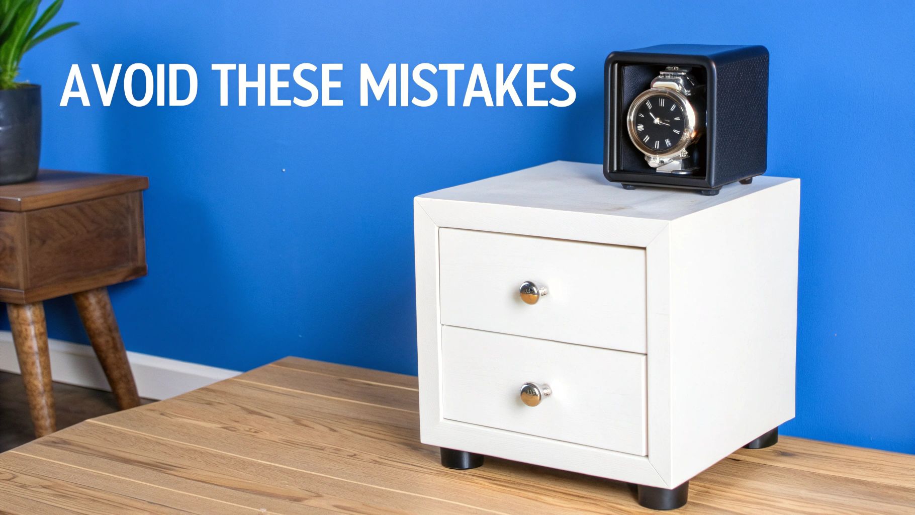 A black watch winder with a gold watch sits on a white nightstand in a blue room.
