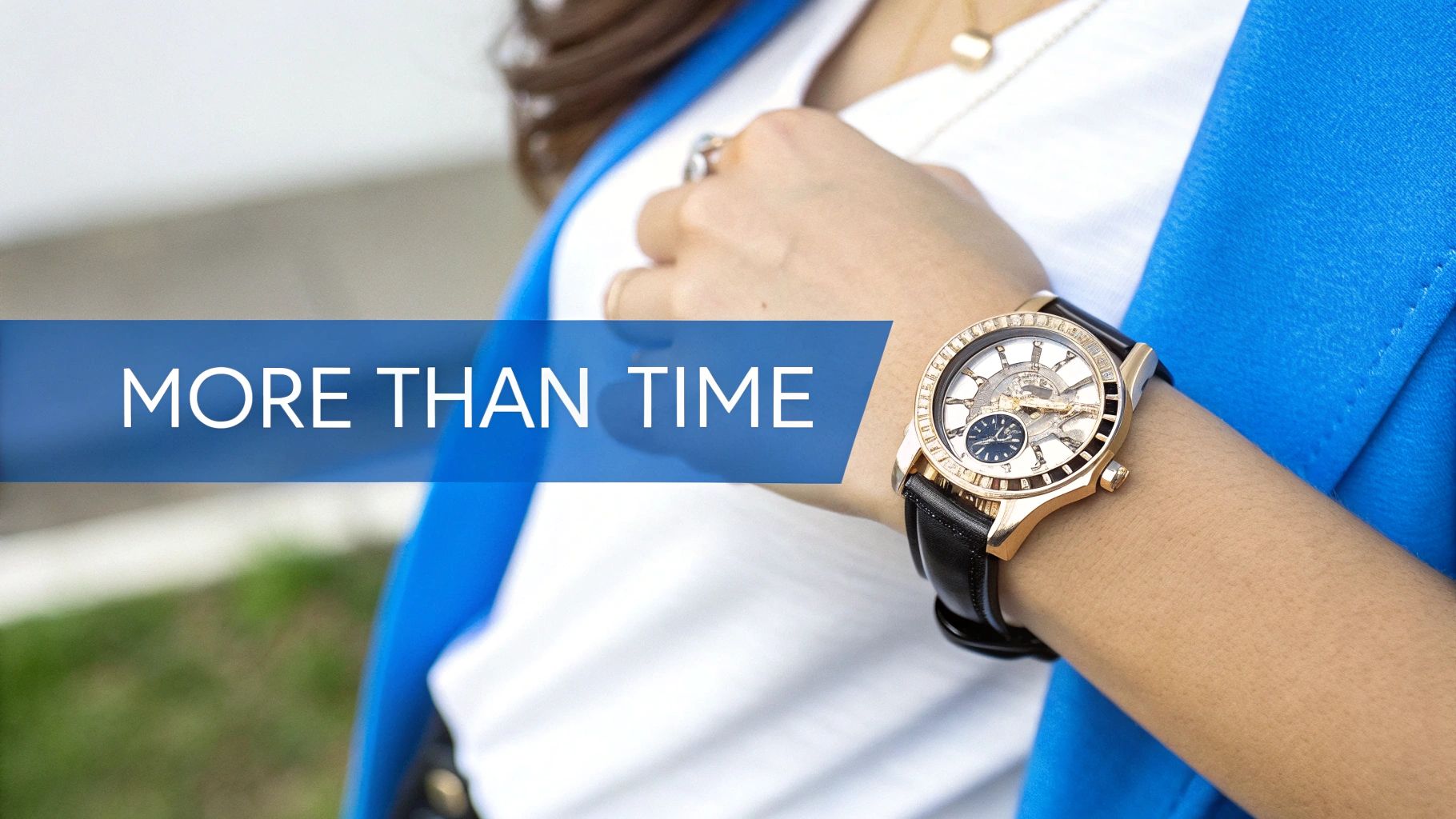 A woman wears a stylish gold-tone skeleton watch with a black leather strap and a blue blazer.