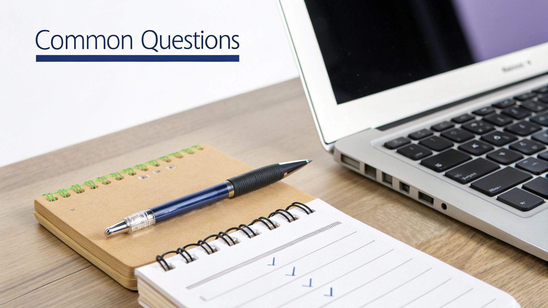A workspace scene featuring a laptop, notebooks, and a pen on a wooden desk with "Common Questions" text.