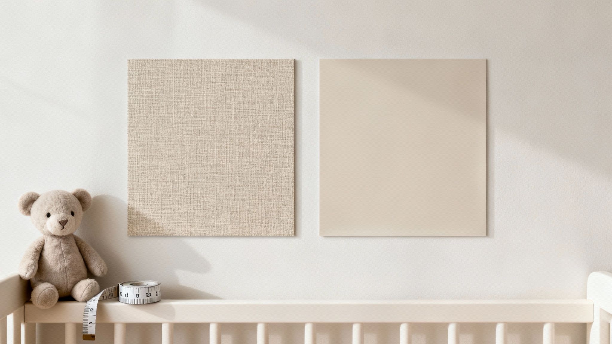 Gezellige babykamer met teddybeer, meetlint, en twee neutrale vierkante wanddecoraties boven een ledikantje.