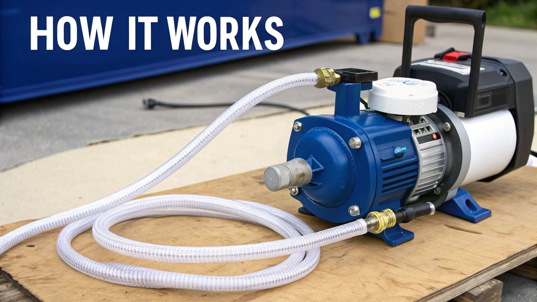 A blue and white portable transfer pump with clear hoses connected, sitting on a wooden pallet.