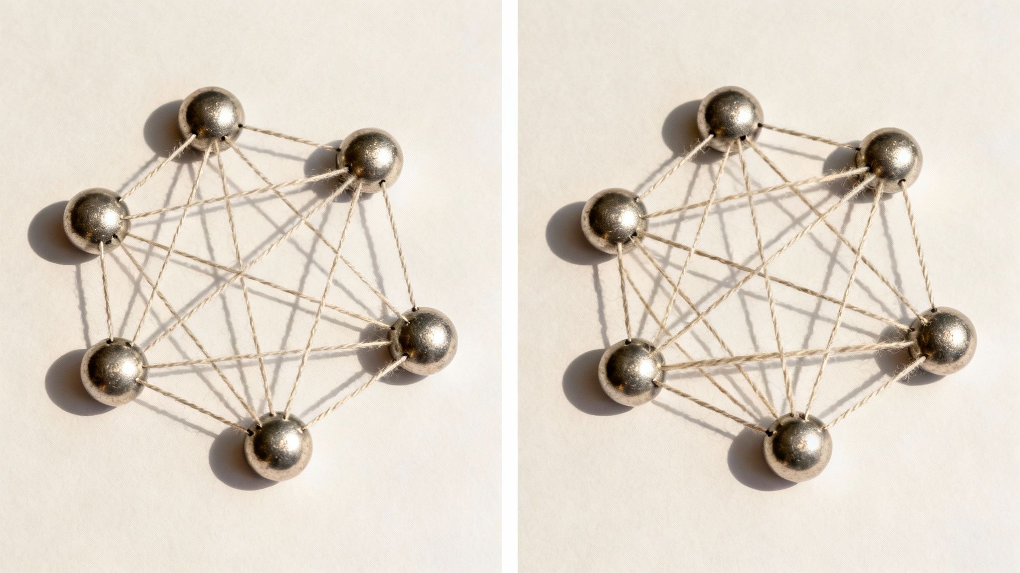 Seven metallic spheres connected by strings, forming a complex network mesh on a light background.