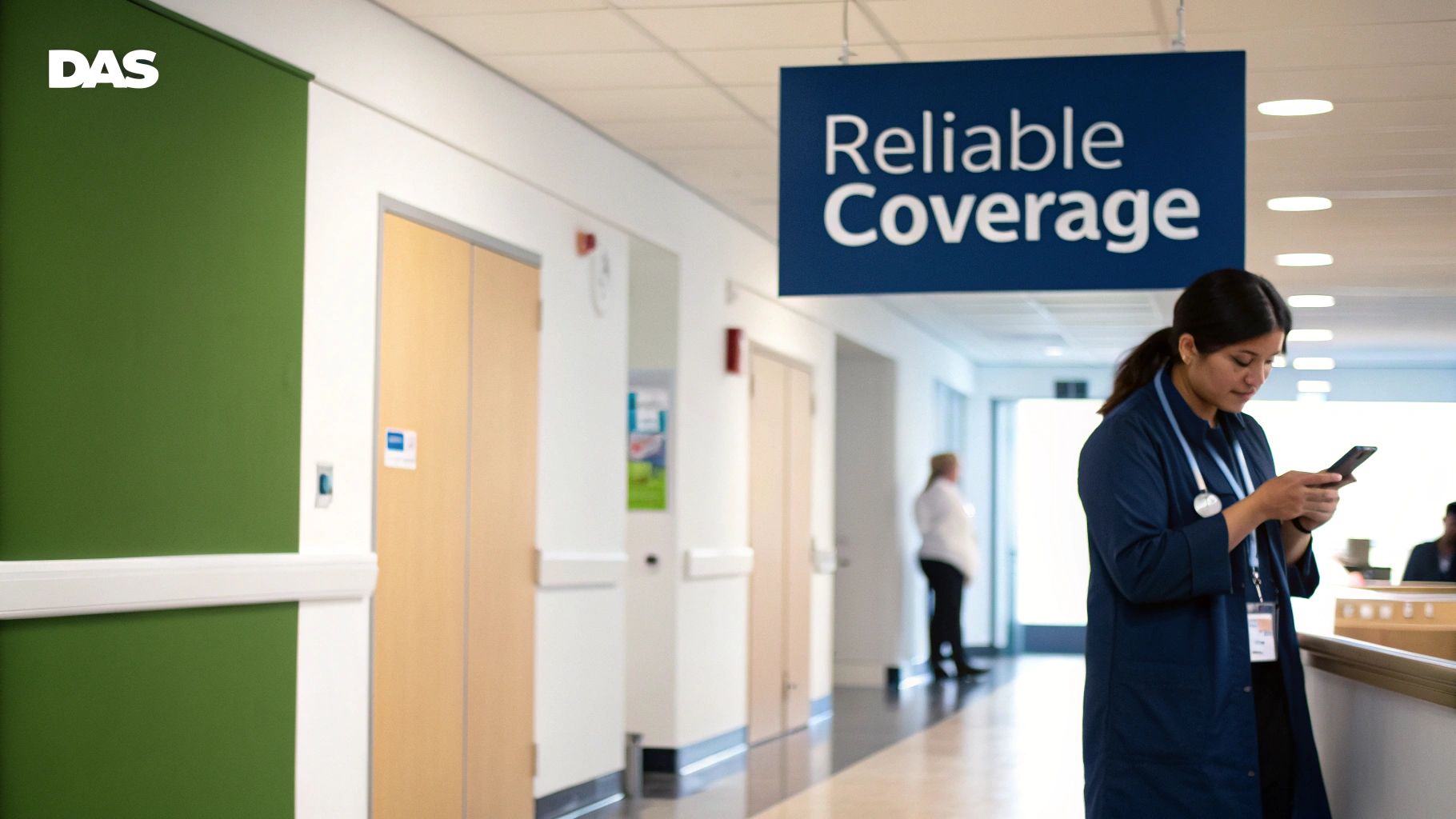 A female medical professional in scrubs checks her phone in a hospital hallway with a 'Reliable Coverage' sign.