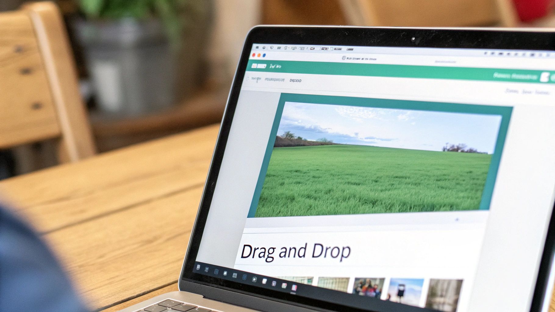 Person views a laptop screen featuring a website with a green field landscape and 'Drag and Drop' functionality.