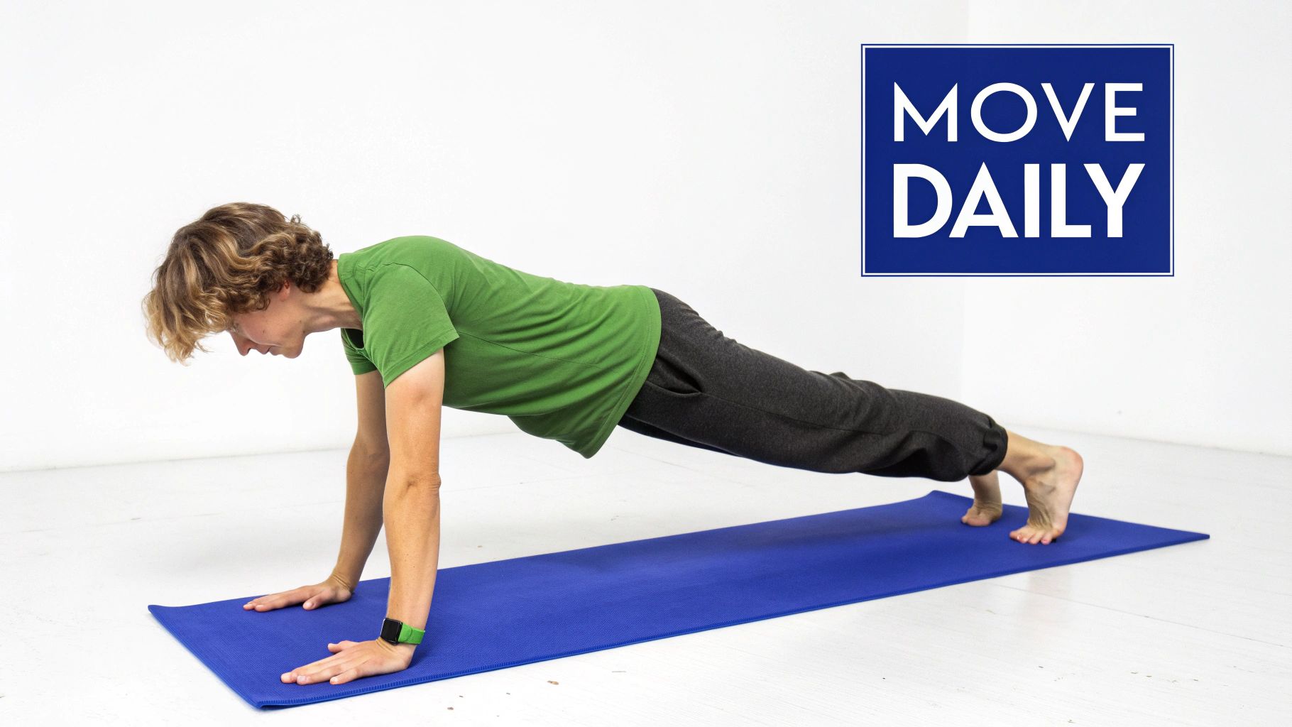 A person in a green shirt and grey pants holds a plank pose on a blue yoga mat.