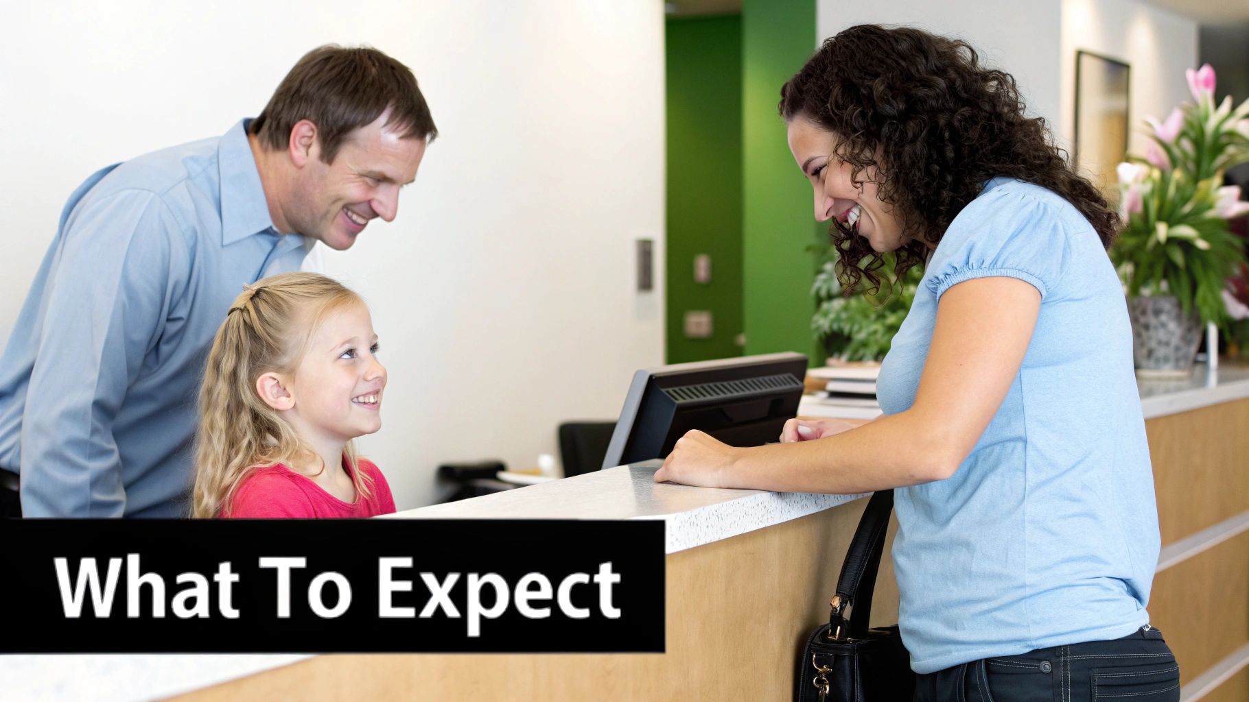 A father and daughter happily checking in at a reception desk with a smiling female staff member.