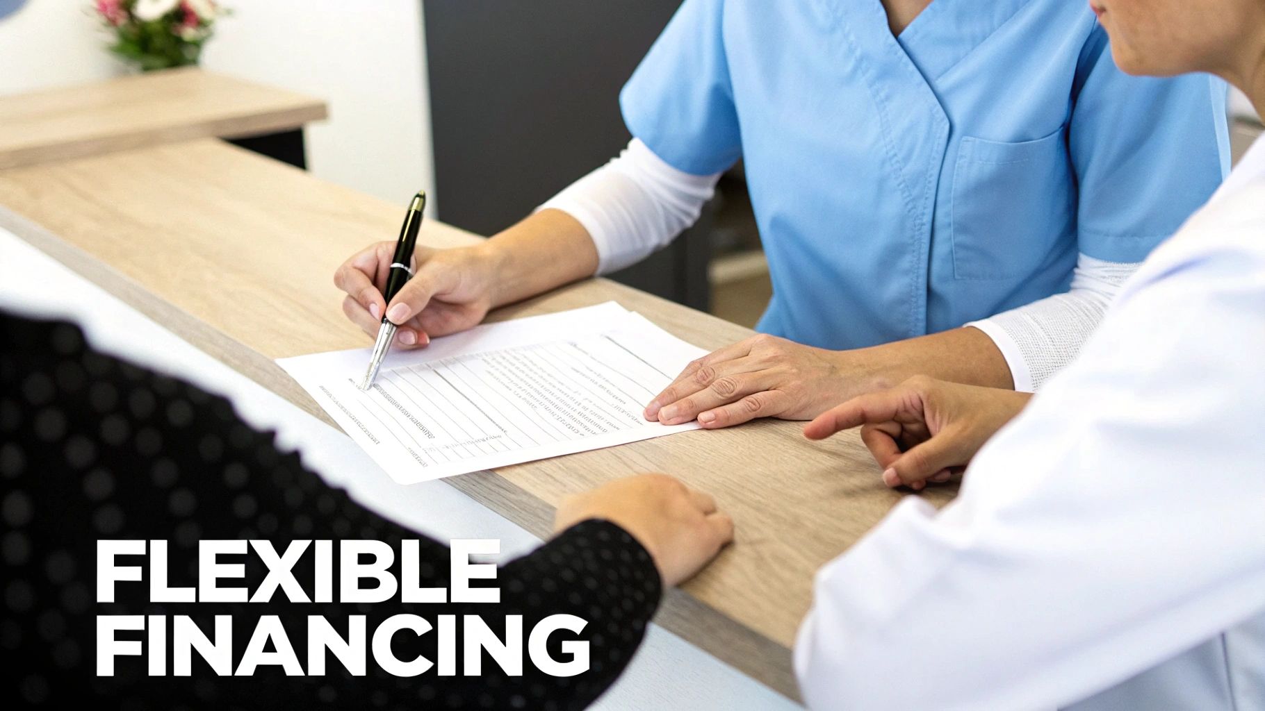 A person in medical scrubs signs a document at a counter, while another in a white coat points.