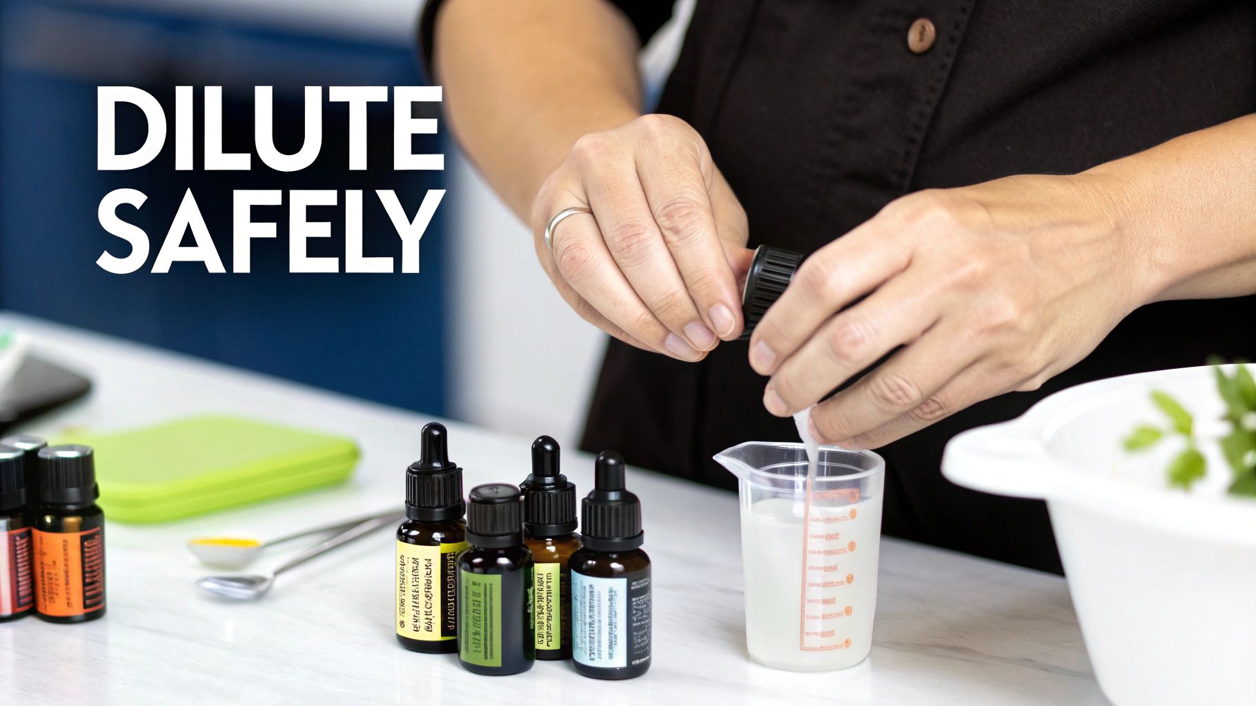 A person safely diluting essential oils into a measuring cup with several dropper bottles on a white counter.