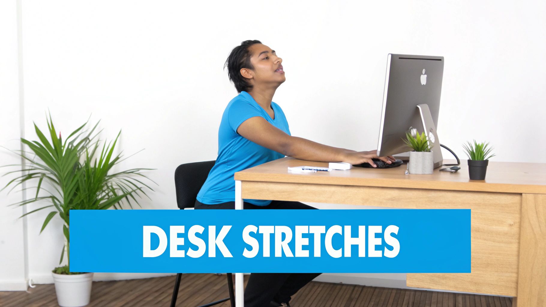 A person in a blue shirt performs a neck stretch while sitting at a desk with a computer.
