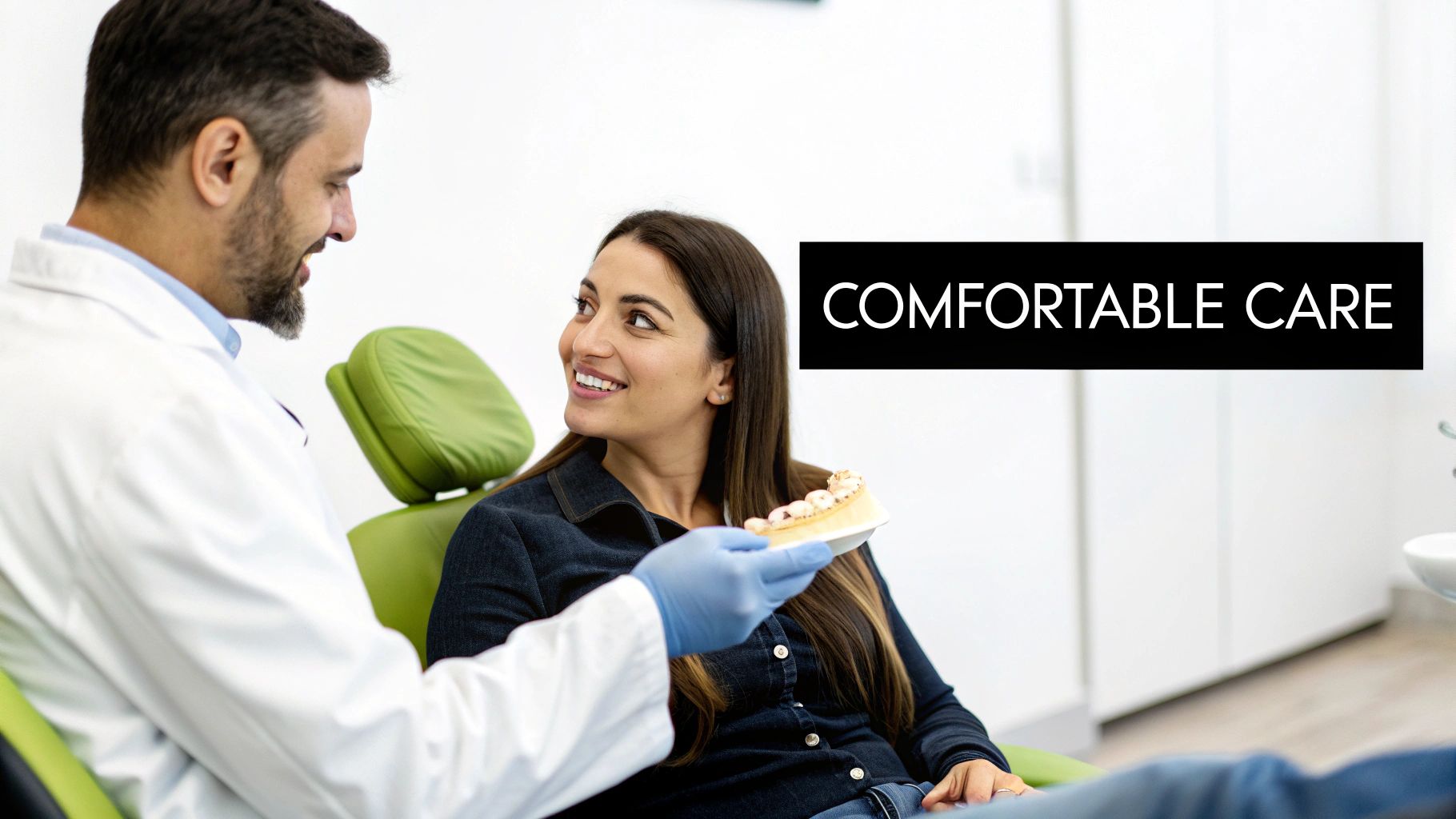 A dentist shows a teeth model to a smiling female patient in a comfortable dental office.