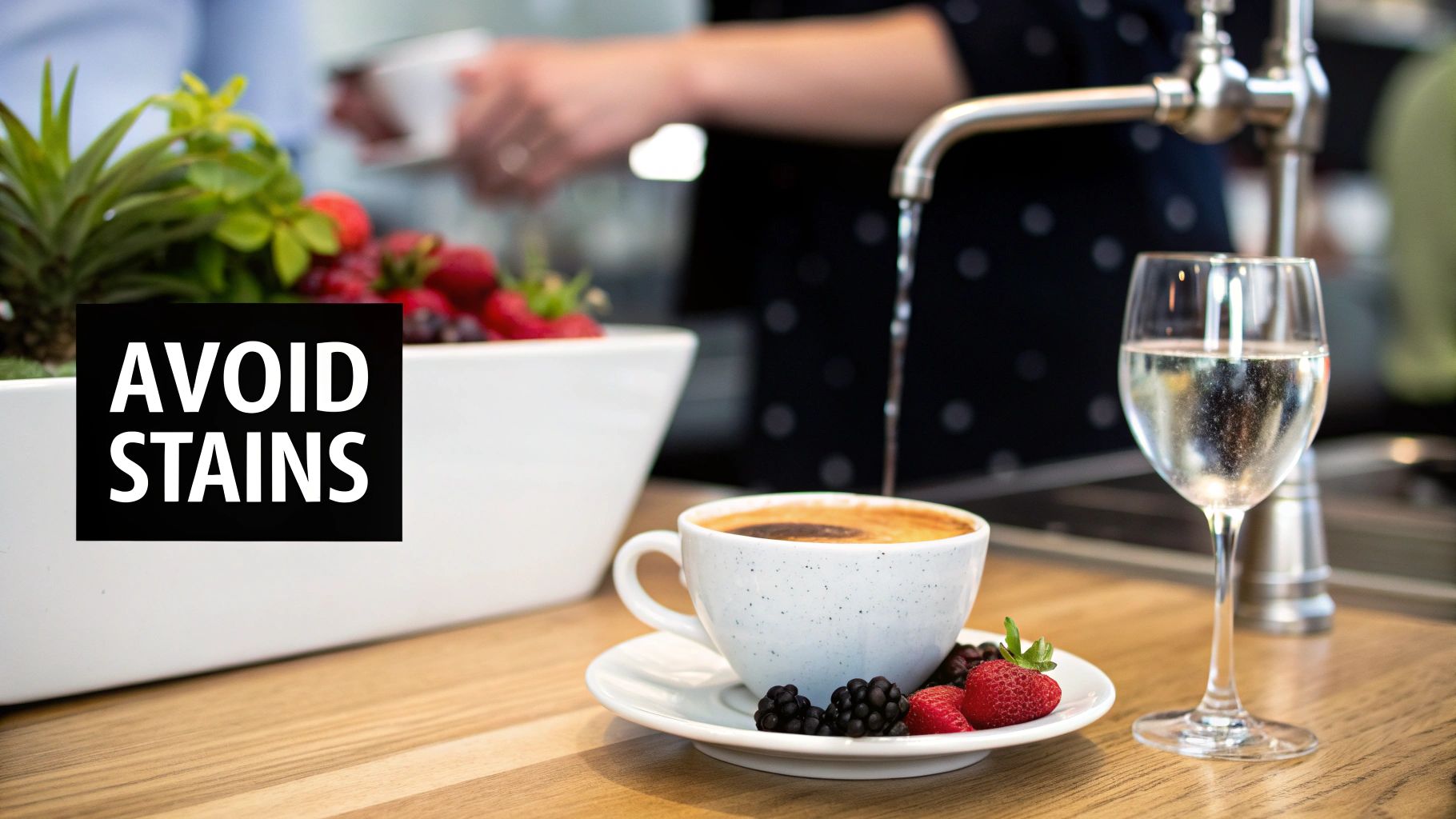 A coffee cup, glass of water, and fresh berries on a counter with an 'AVOID STAINS' sign.