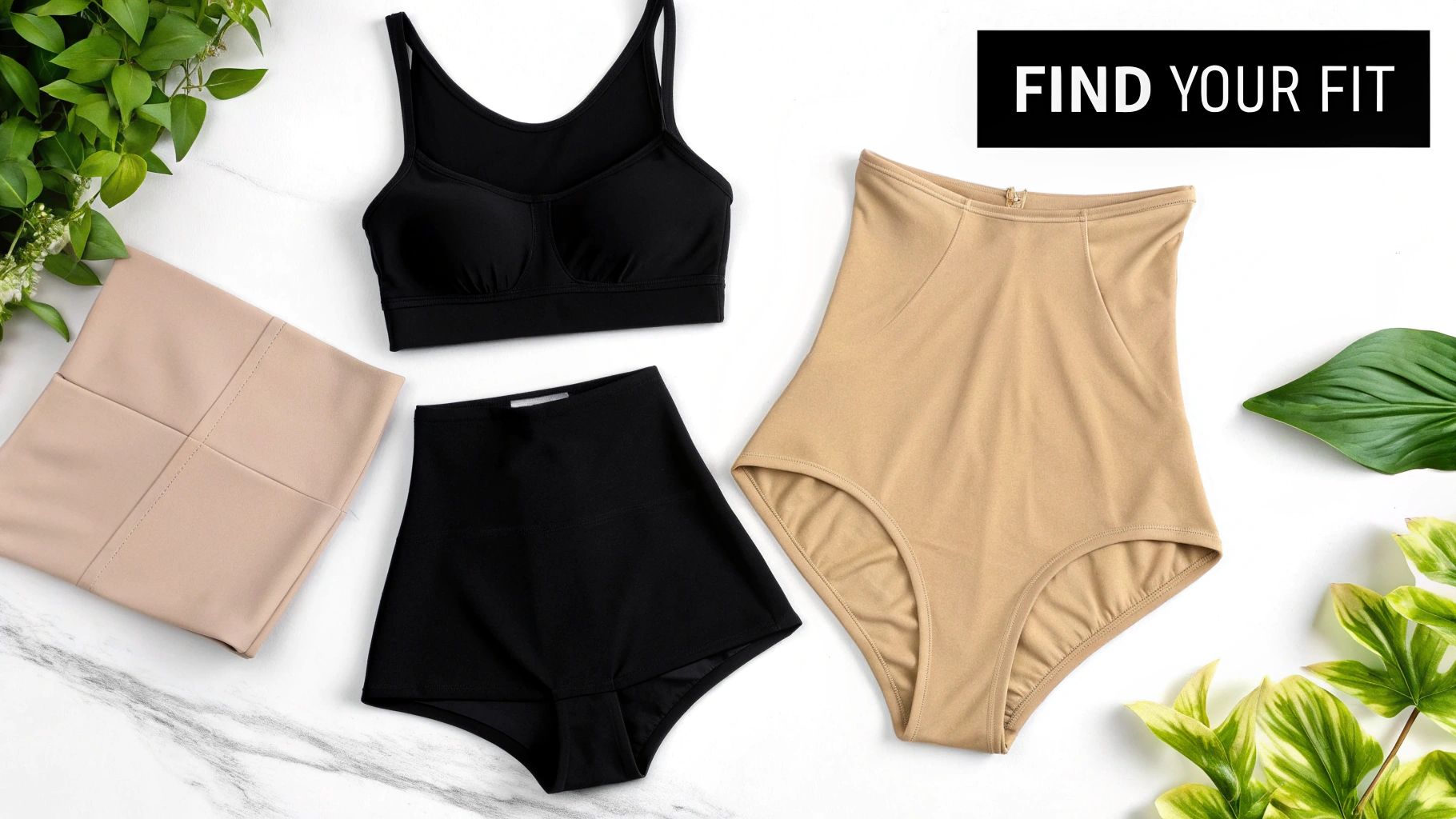 A flat lay of various black and beige shapewear and lingerie pieces, surrounded by green plants.