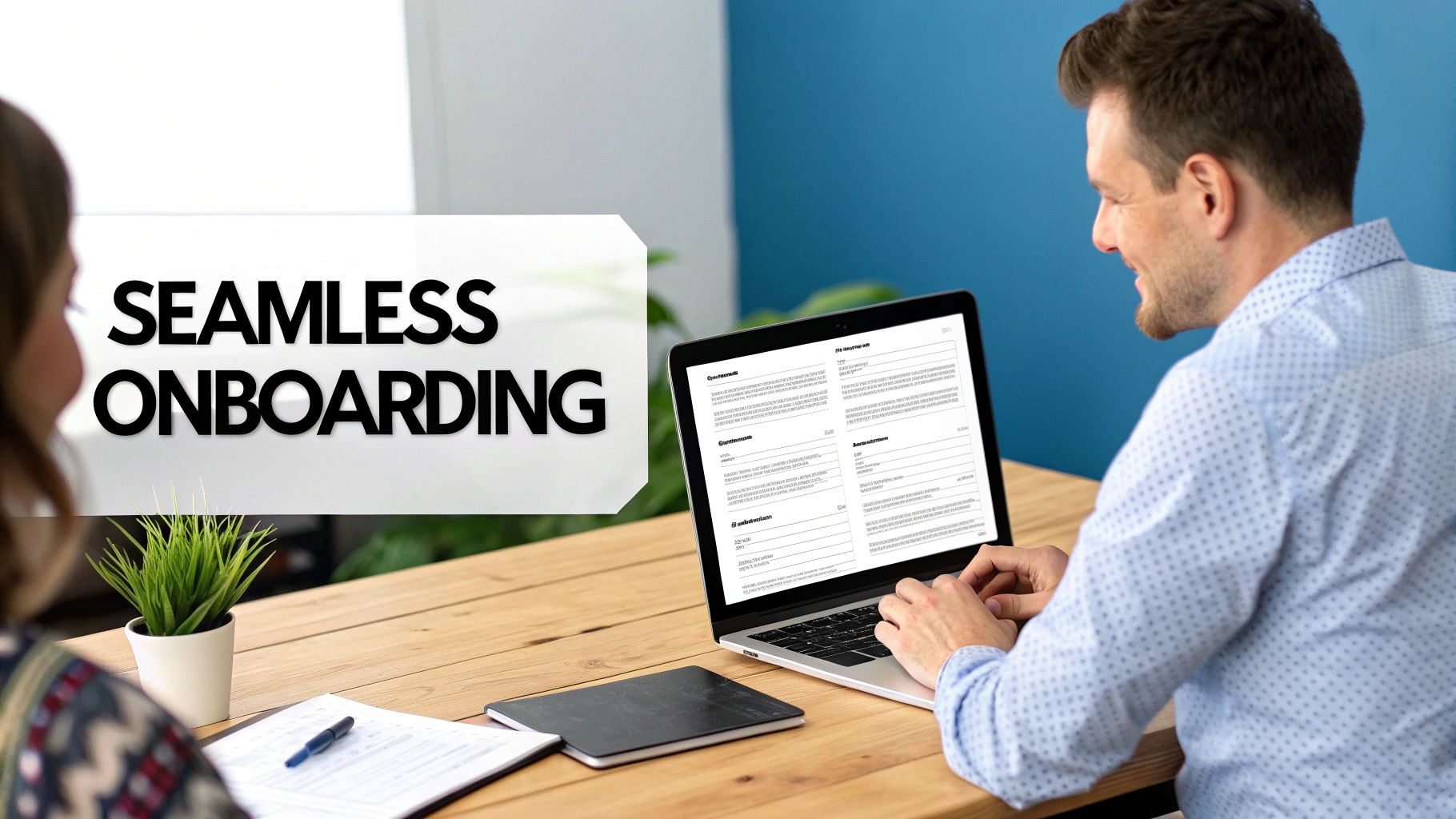 A man smiling while using a laptop for seamless digital onboarding, with a woman partially visible.