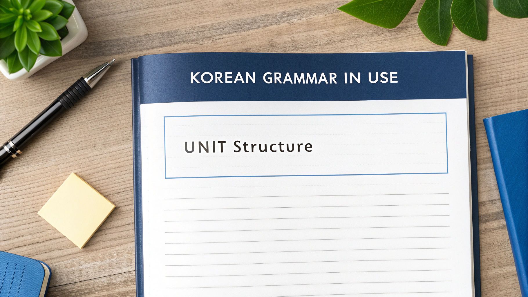 Korean Grammar in Use textbook opened to Unit Structure page on wooden desk with pen and plants