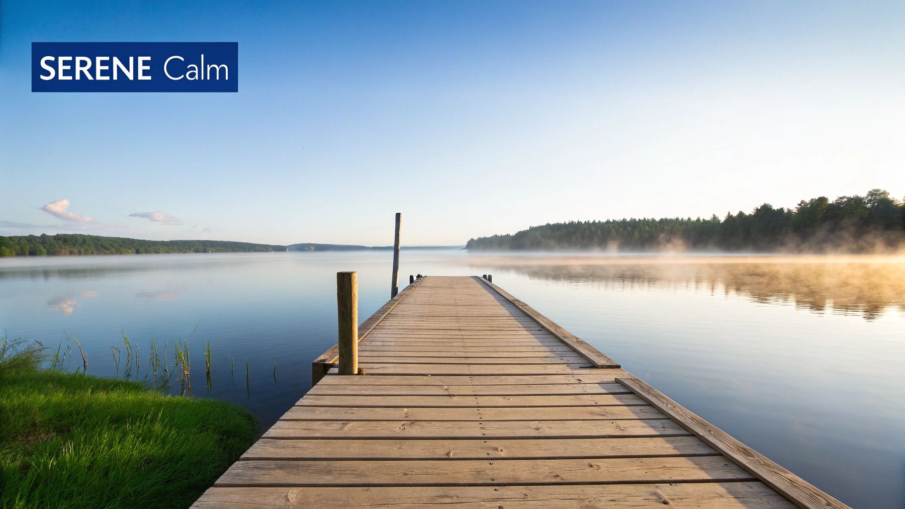 A serene lakeside view with calm water and mountains in the background.