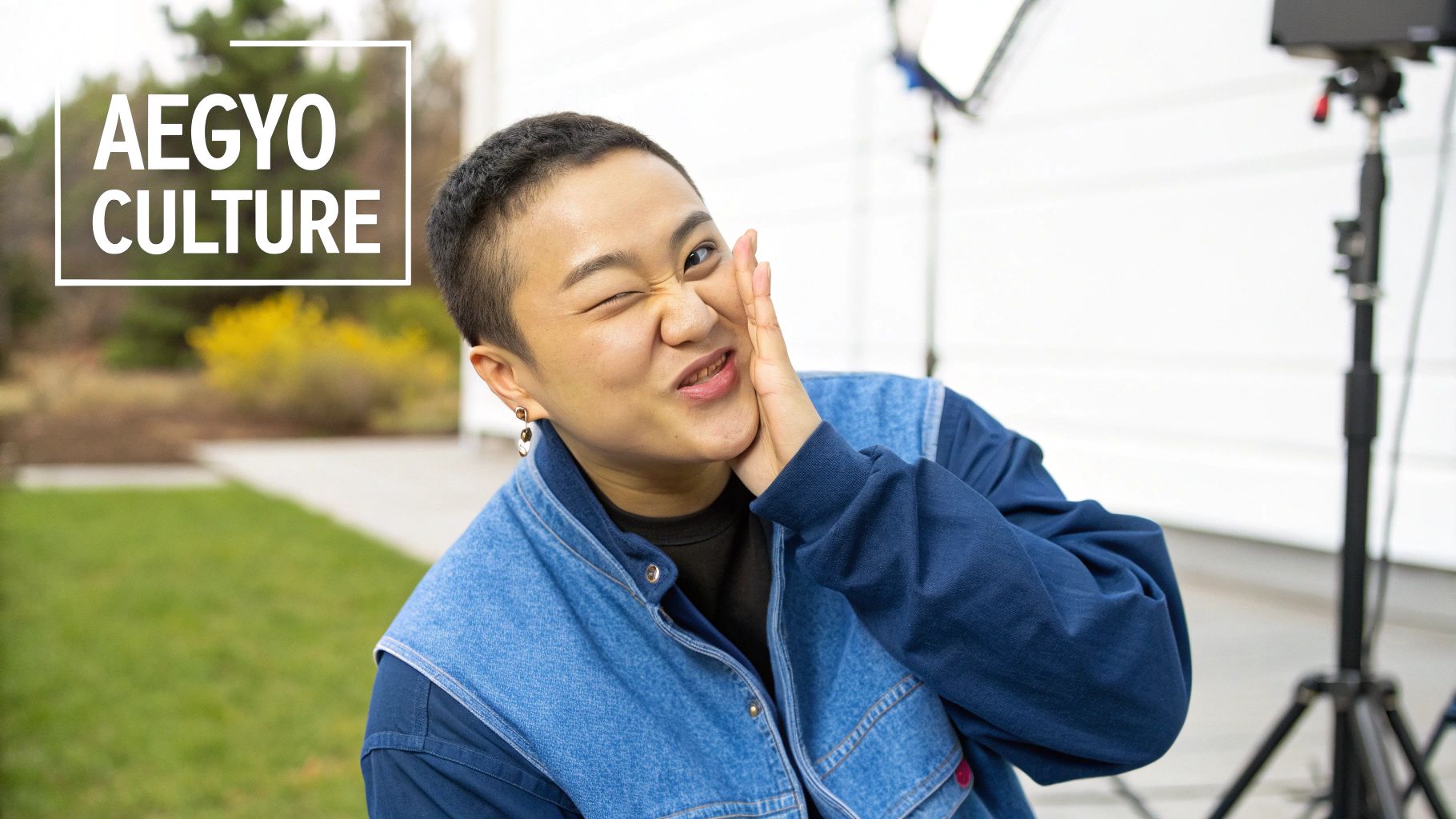 A person with a short haircut winks and makes a cute, playful aegyo pose.