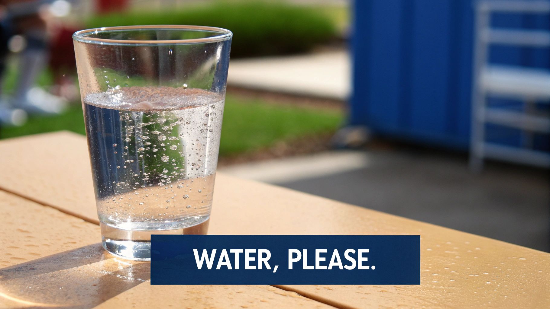 A refreshing glass of water with many bubbles sits on a sunlit wooden picnic table outdoors.
