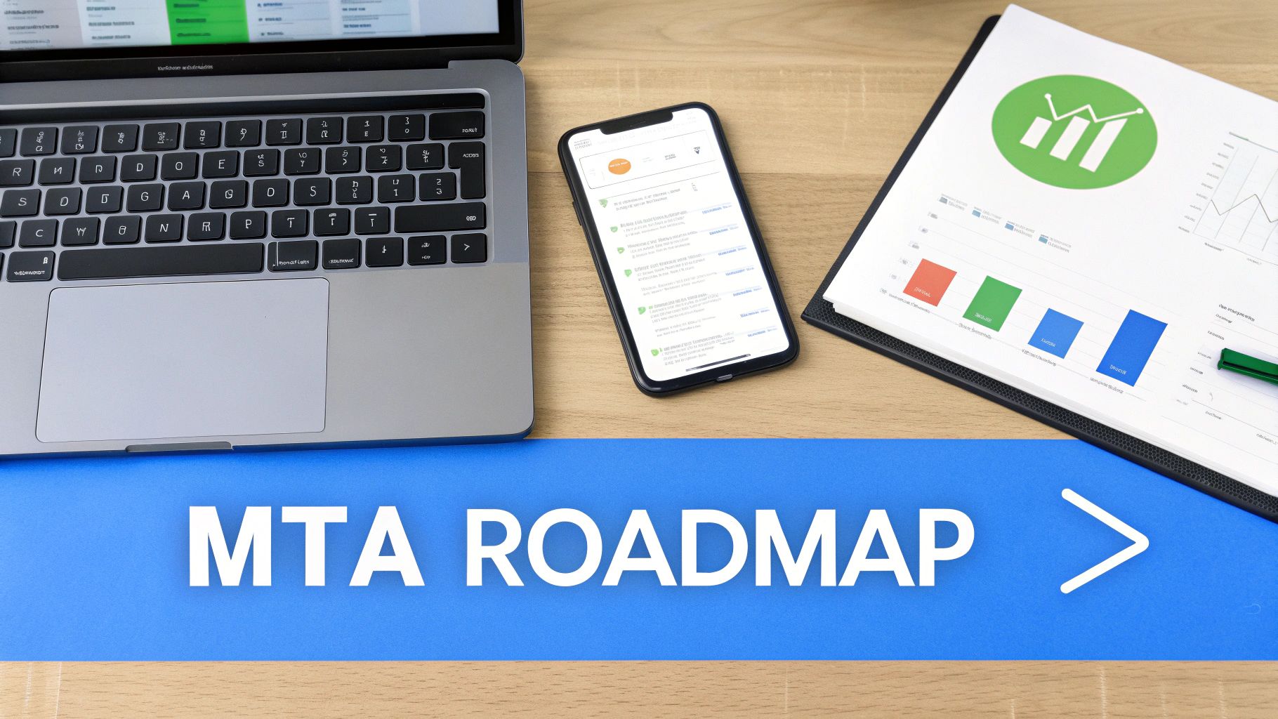 A top-down view of a modern workspace featuring a laptop, smartphone, financial charts, and an "MTA ROADMAP" banner.