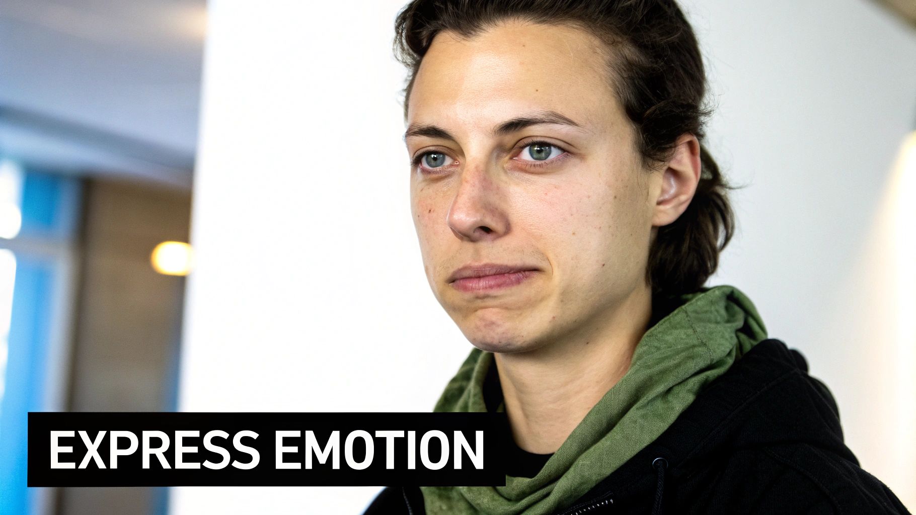 Close-up of a person with blue eyes and a thoughtful, subtle expression, wearing a hoodie.