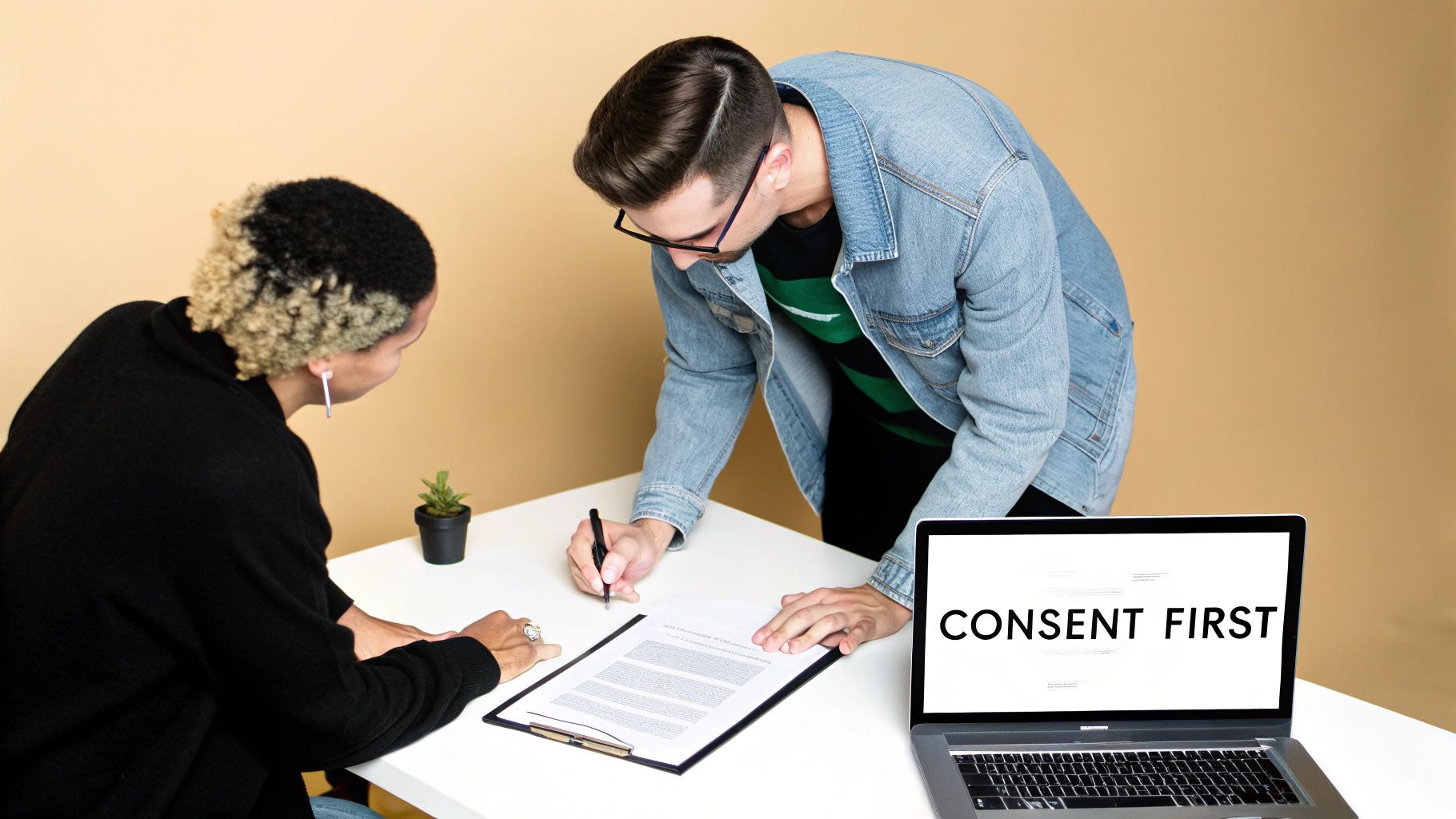 A man signing a document with a woman observing, while a laptop shows 'CONSENT FIRST'.