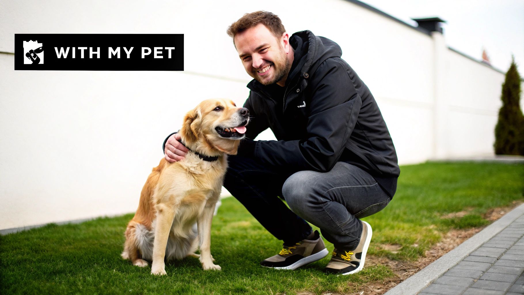 A smiling man kneels on green grass, petting a happy golden retriever dog next to a white wall with 'WITH MY PET' logo.