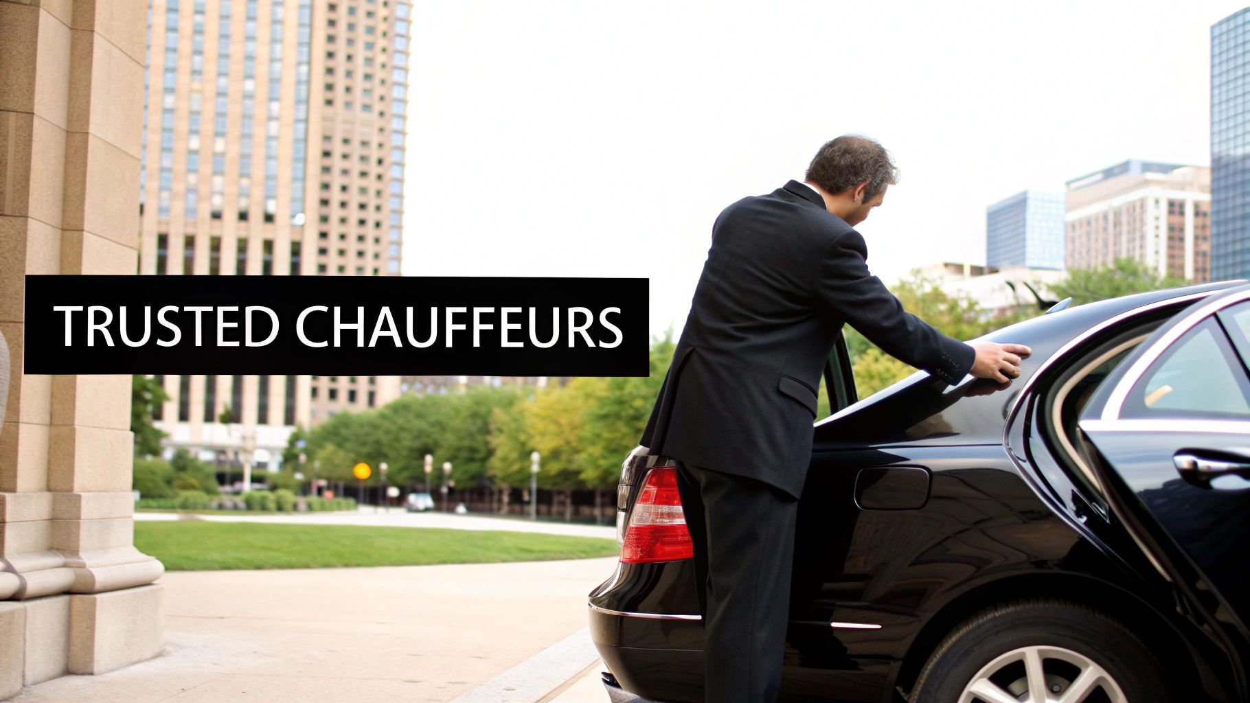 A professional chauffeur in a black suit closes the trunk of a sleek black luxury car, offering premium service.