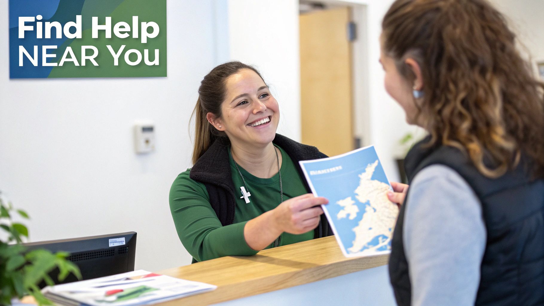 Smiling woman at help desk hands a map brochure to a client under a 'Find Help' sign.