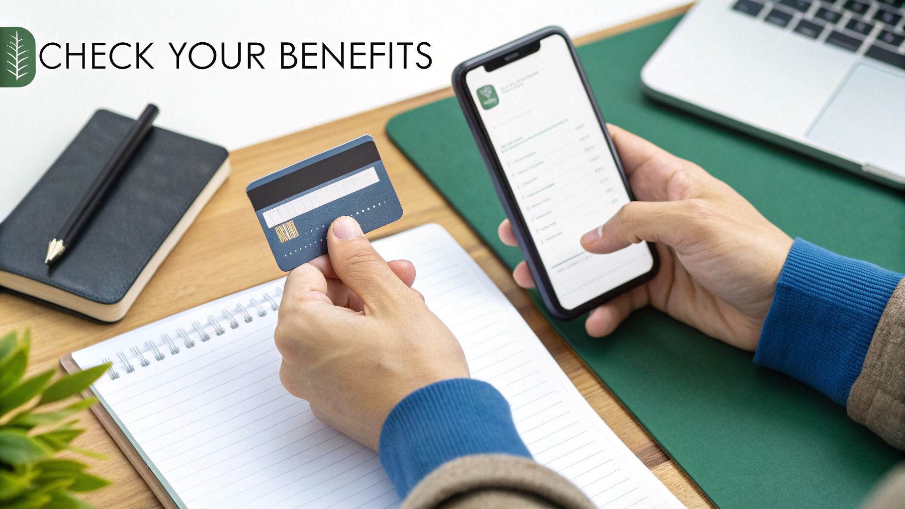 Hands holding a credit card and a smartphone displaying benefits, with a notebook and laptop on a desk.