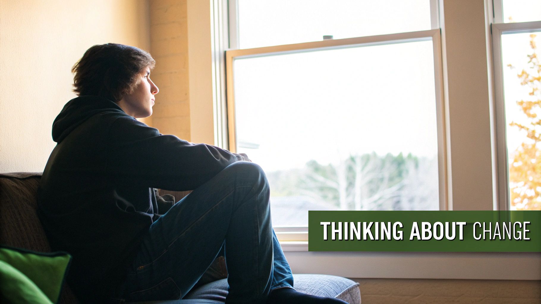 Thoughtful young person sitting by window contemplating personal growth and life changes