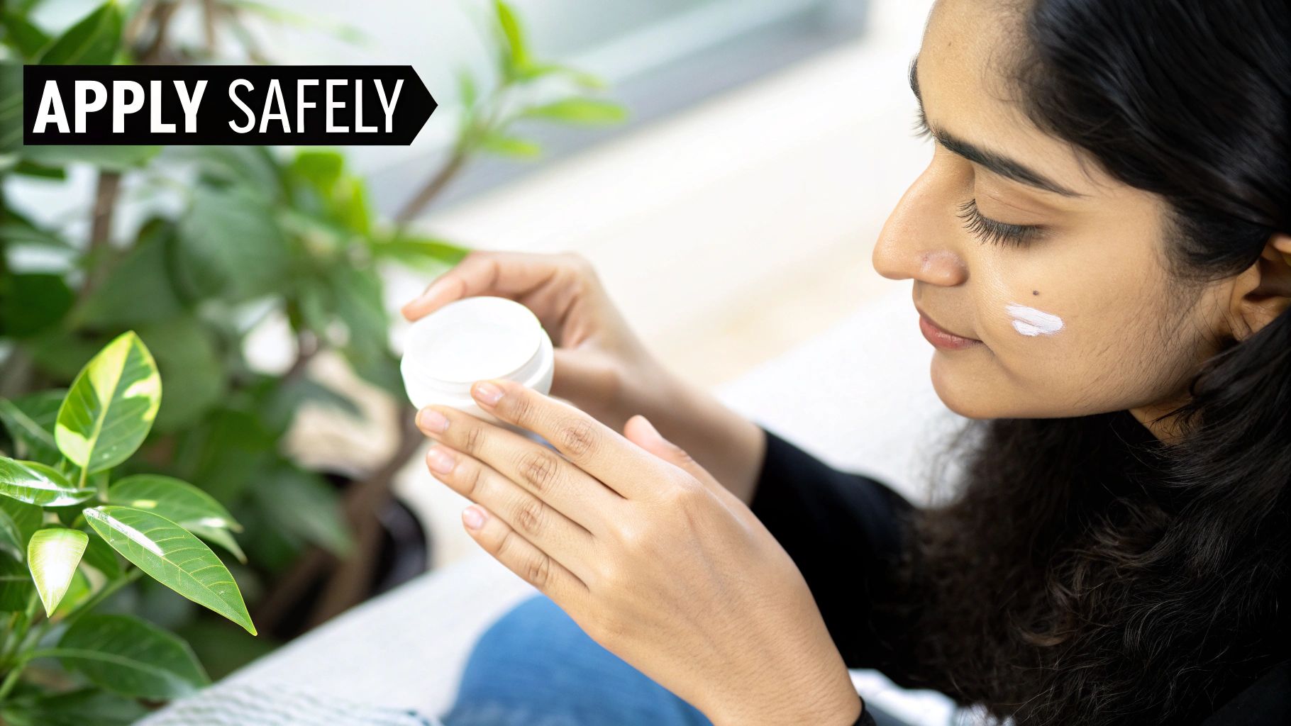 A person applying a thin layer of cream to their face in a clean, minimalist bathroom setting.