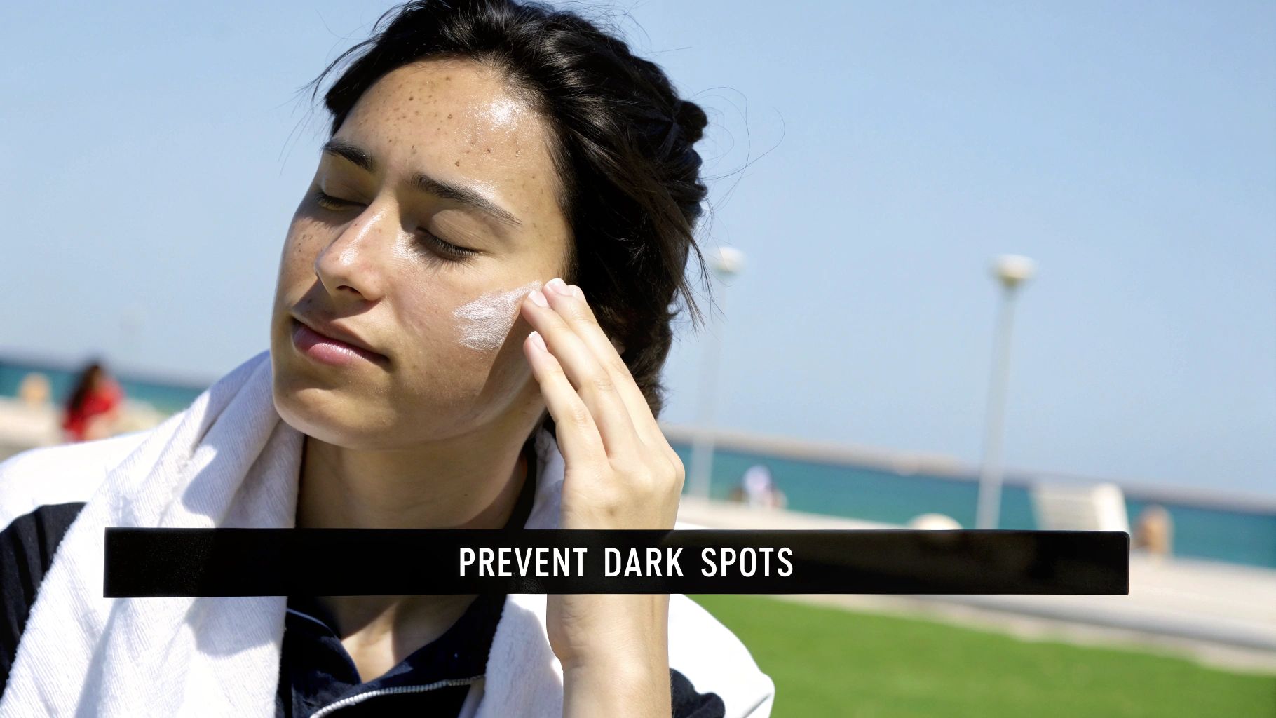 A person applying sunscreen to their face in a sunny outdoor setting.