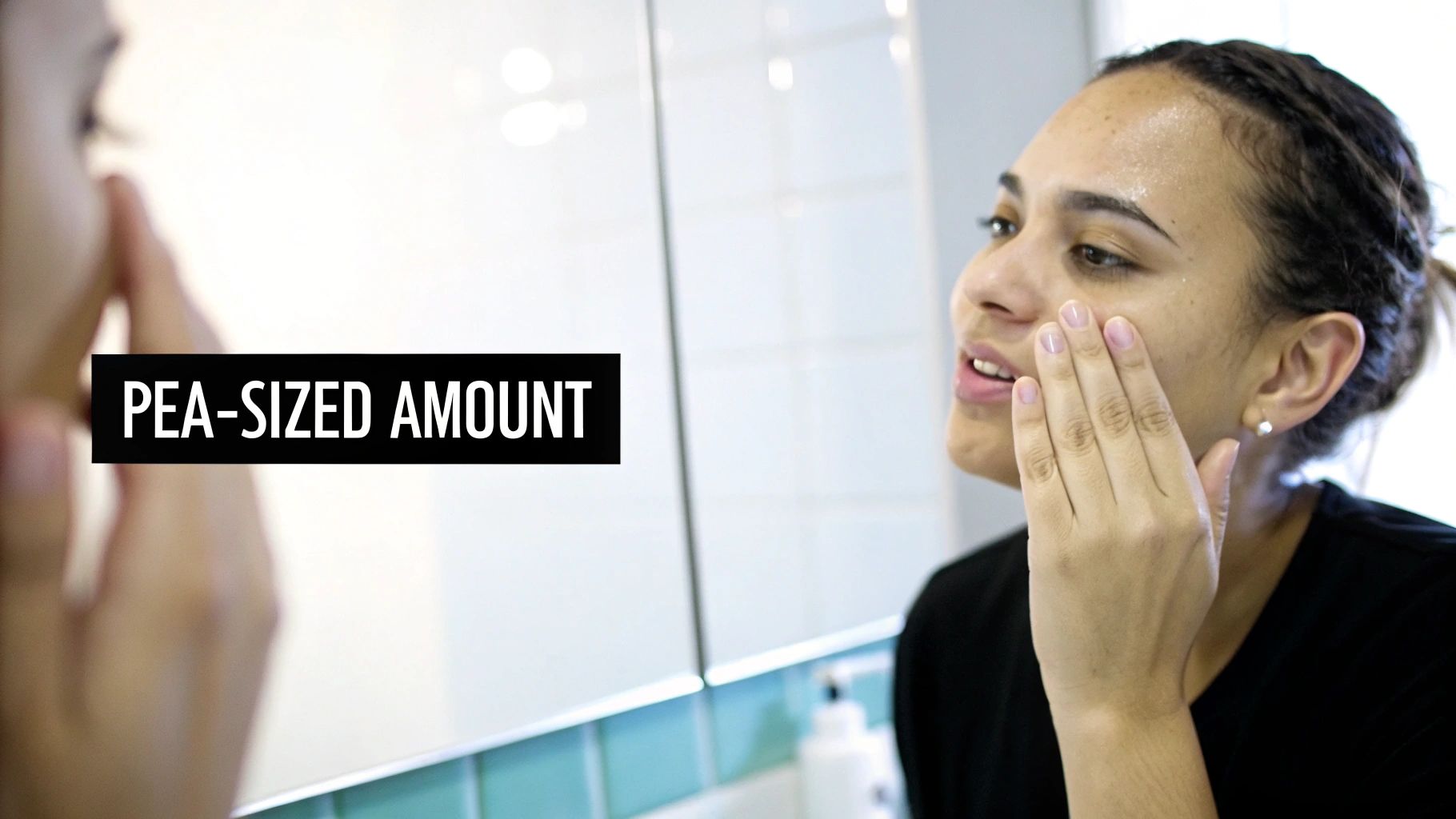 A woman applies a pea-sized amount of moisturizer to her face, reflected in a mirror.