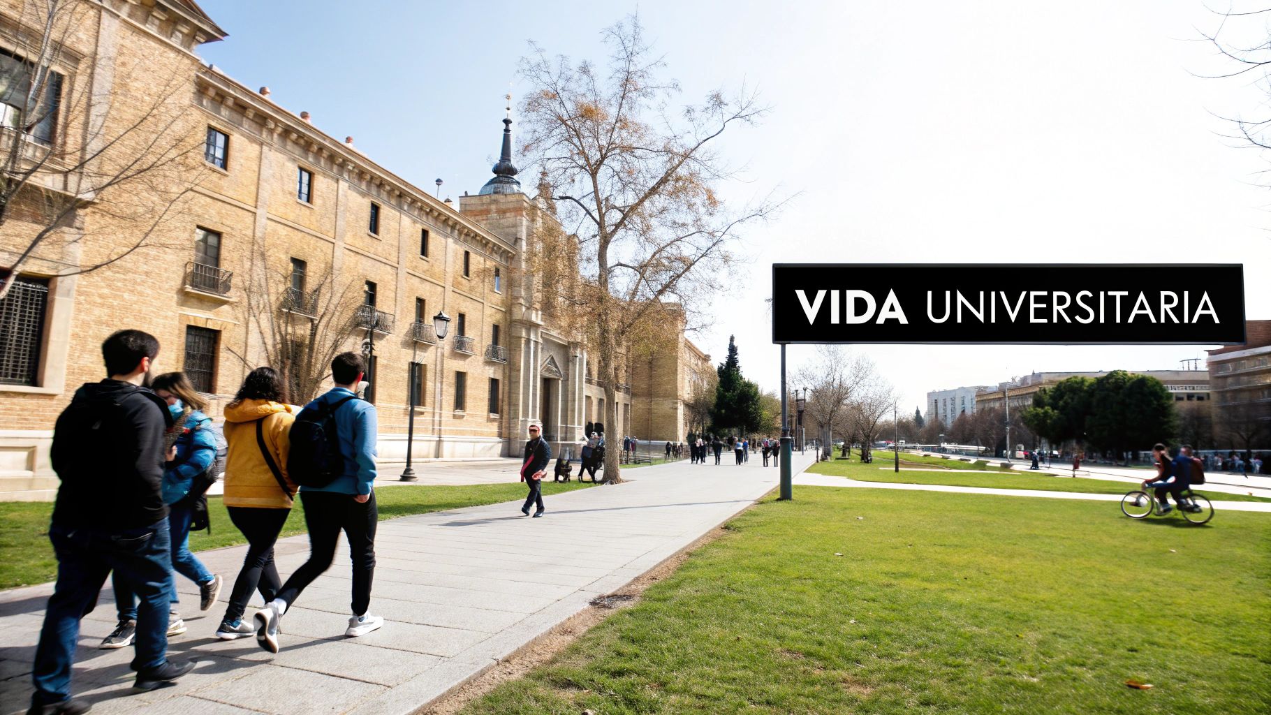 Estudiantes caminan por un campus universitario soleado con un edificio histórico y un cartel de 'Vida Universitaria'.