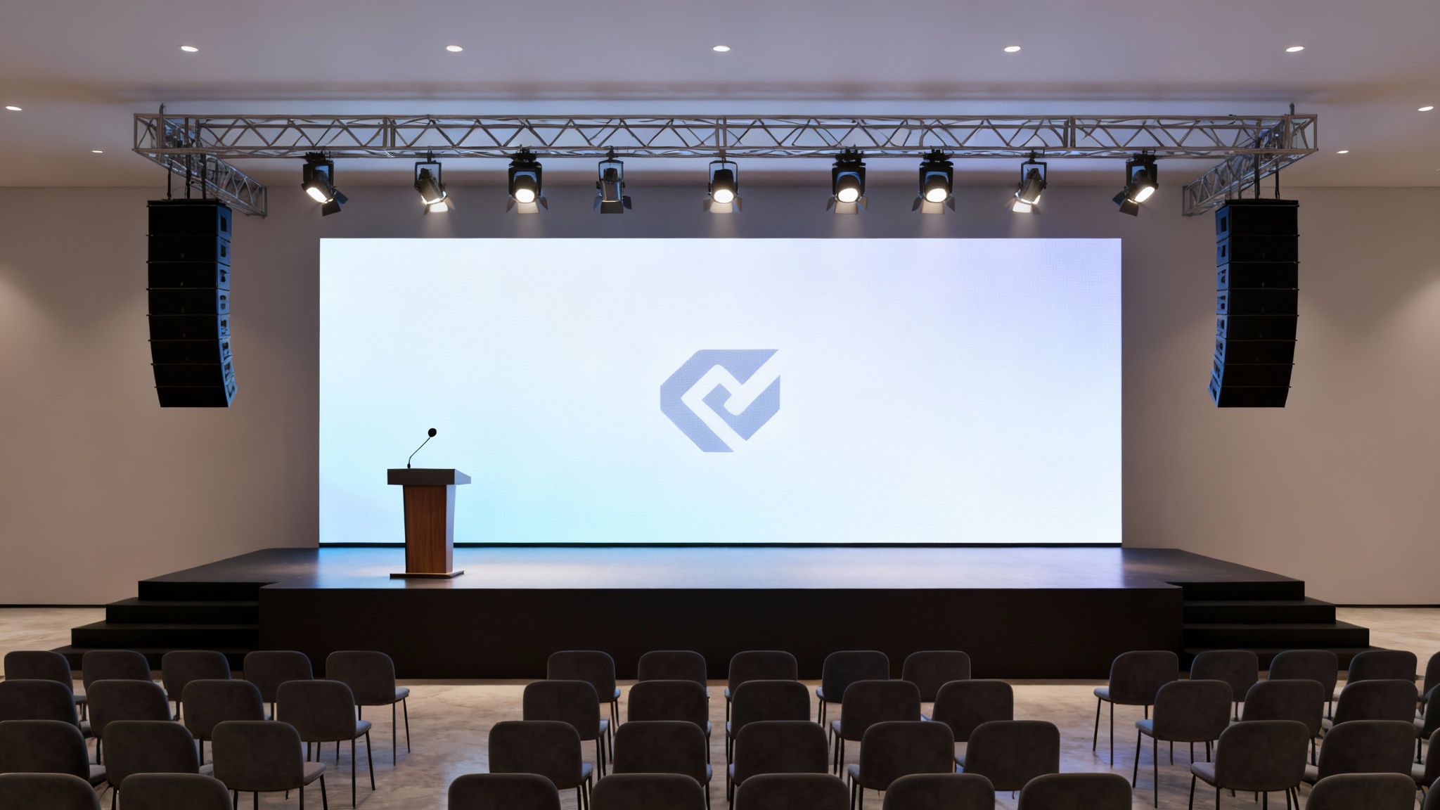 An empty modern auditorium stage with a large screen, podium, microphone, and overhead sound system.