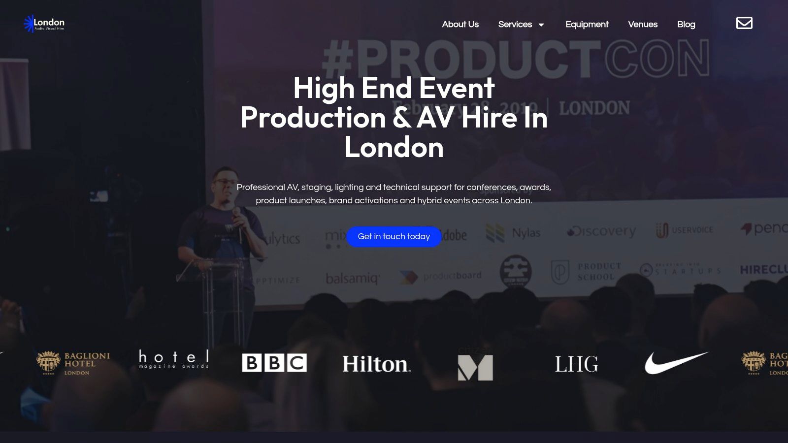 A professional event setup by London Audio Visual Hire showing a stage, screen, and lighting for a corporate conference.