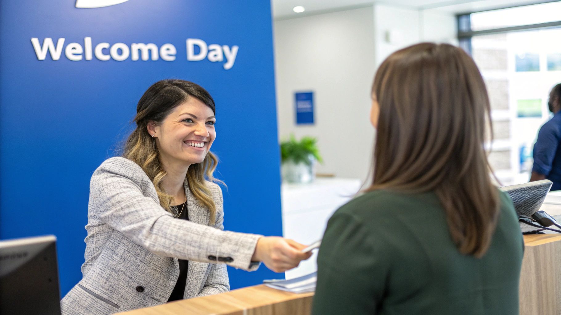 A diverse group of new employees is warmly greeted in a modern office space, receiving welcome kits and engaging in conversation with their new team members.