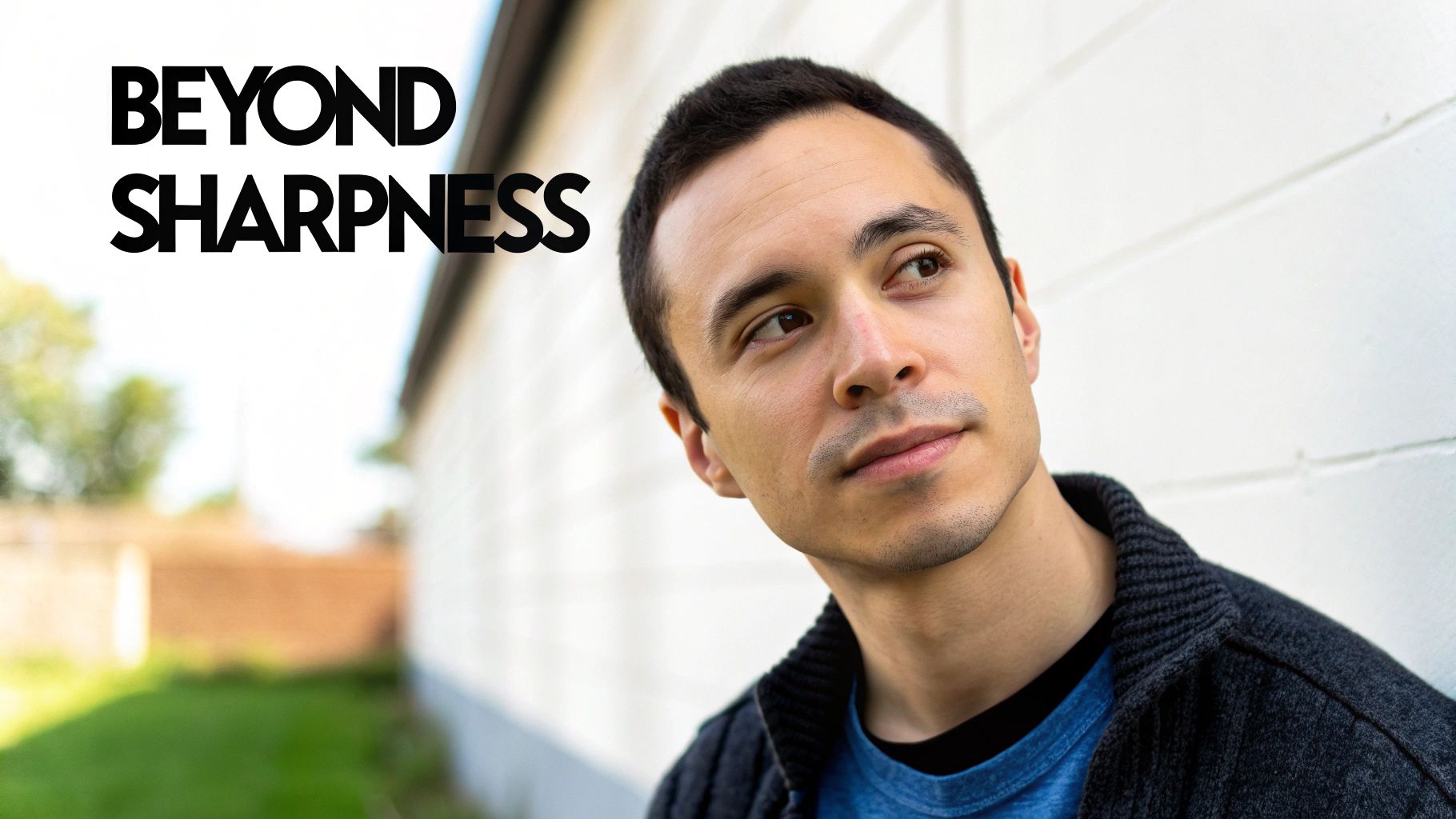 A man looks thoughtfully upwards, leaning against a white wall with text 'BEYOND SHARPNESS'.