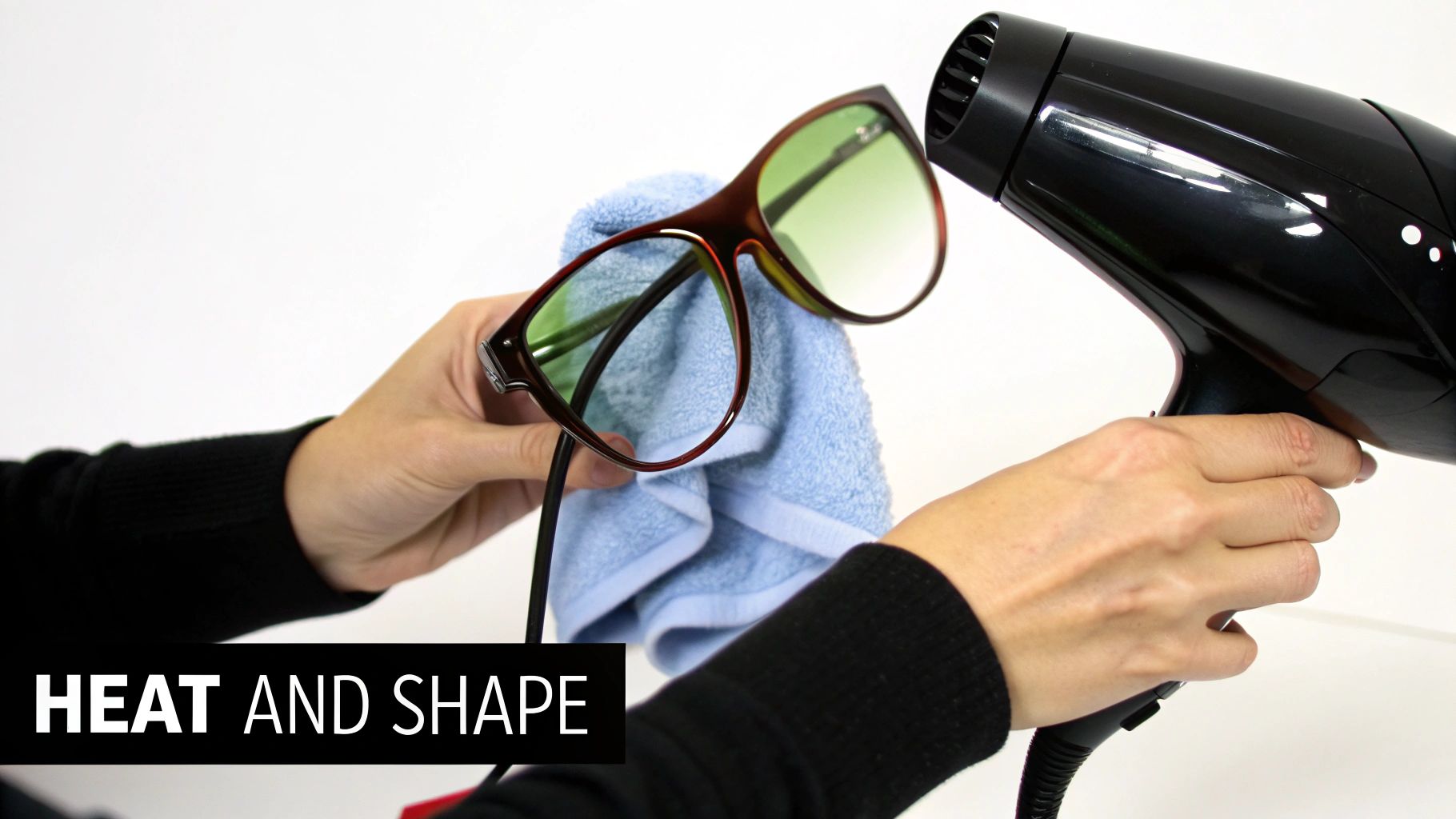 A person uses a hairdryer to heat glasses wrapped in a towel for adjustment.