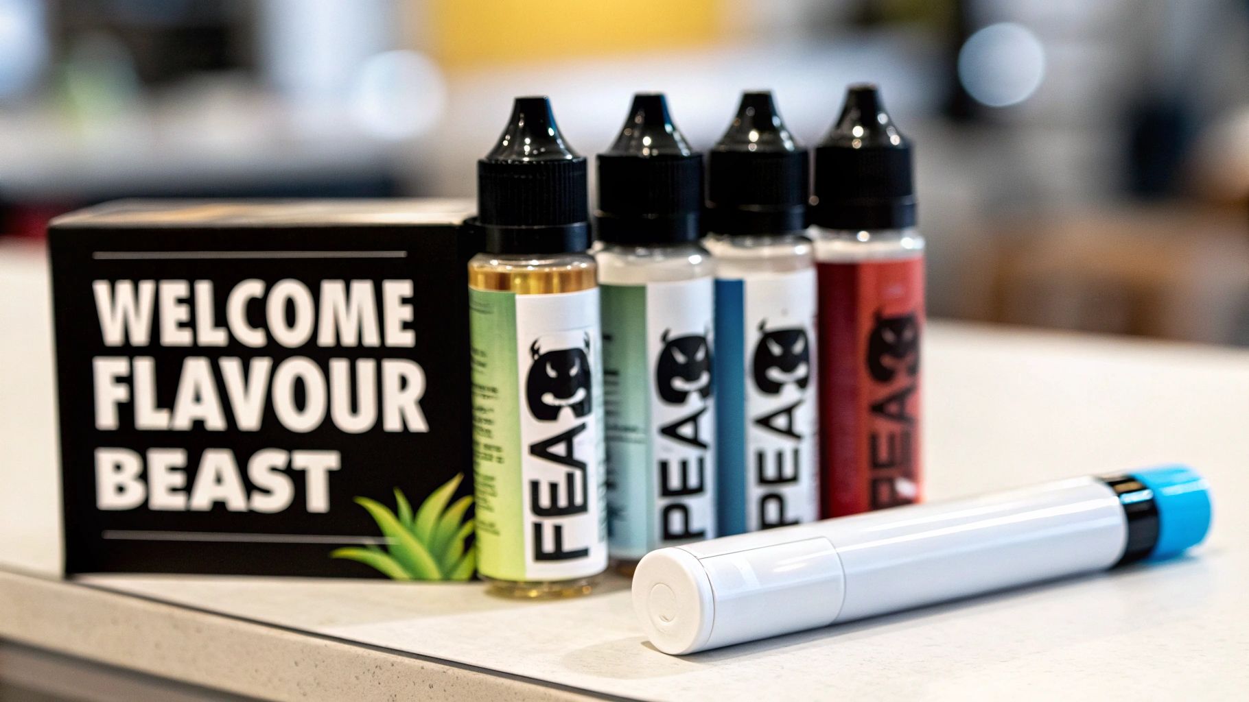 A box labeled 'WELCOME FLAVOUR BEAST' sits next to four bottles of colorful vape juice and a white vape pen.