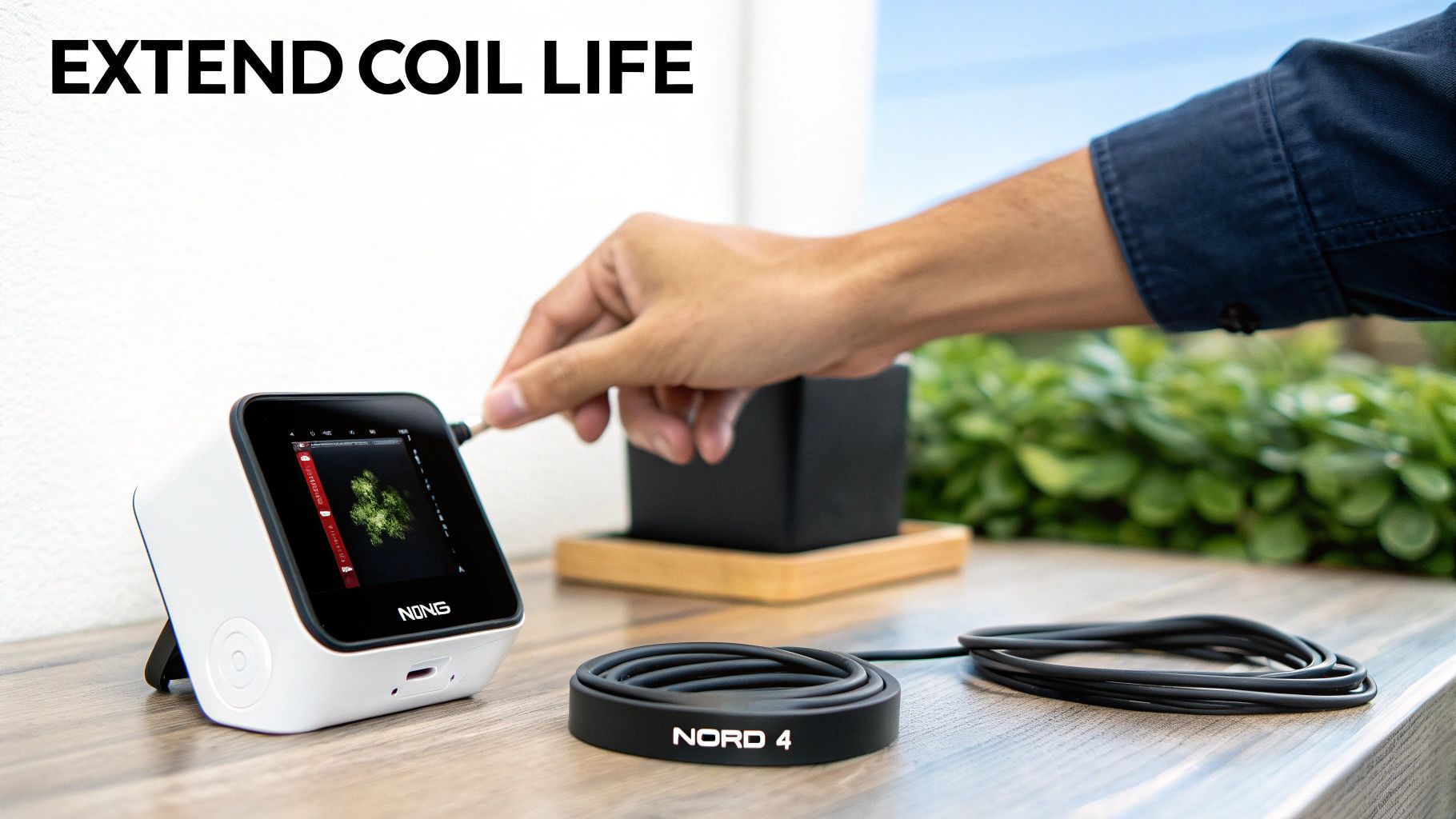 Hand plugging a cable into a NONG device on a wooden table, with a NORD 4 cable organizer nearby, promoting coil life.