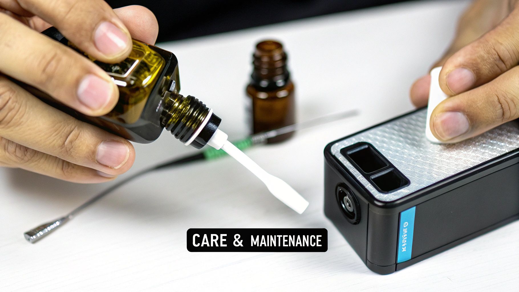 A person's hands maintaining a black device with a dropper bottle and cleaning tool on a white surface.