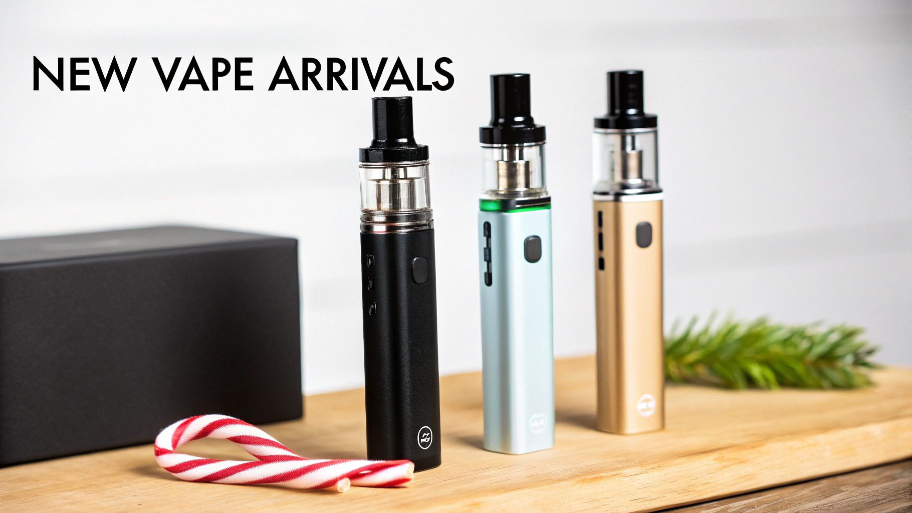 Three vape pens in black, blue, and gold, with a candy cane on a wooden surface.