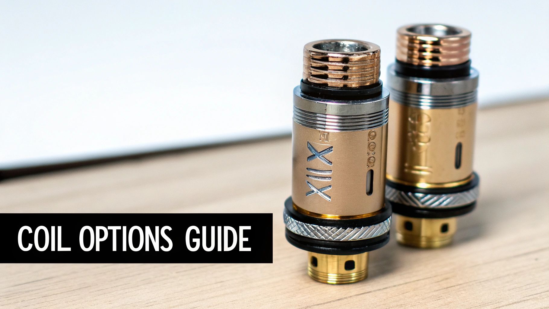 Two metallic gold vape tanks, one marked 'XIX', on a desk with a 'COIL OPTIONS GUIDE' banner.