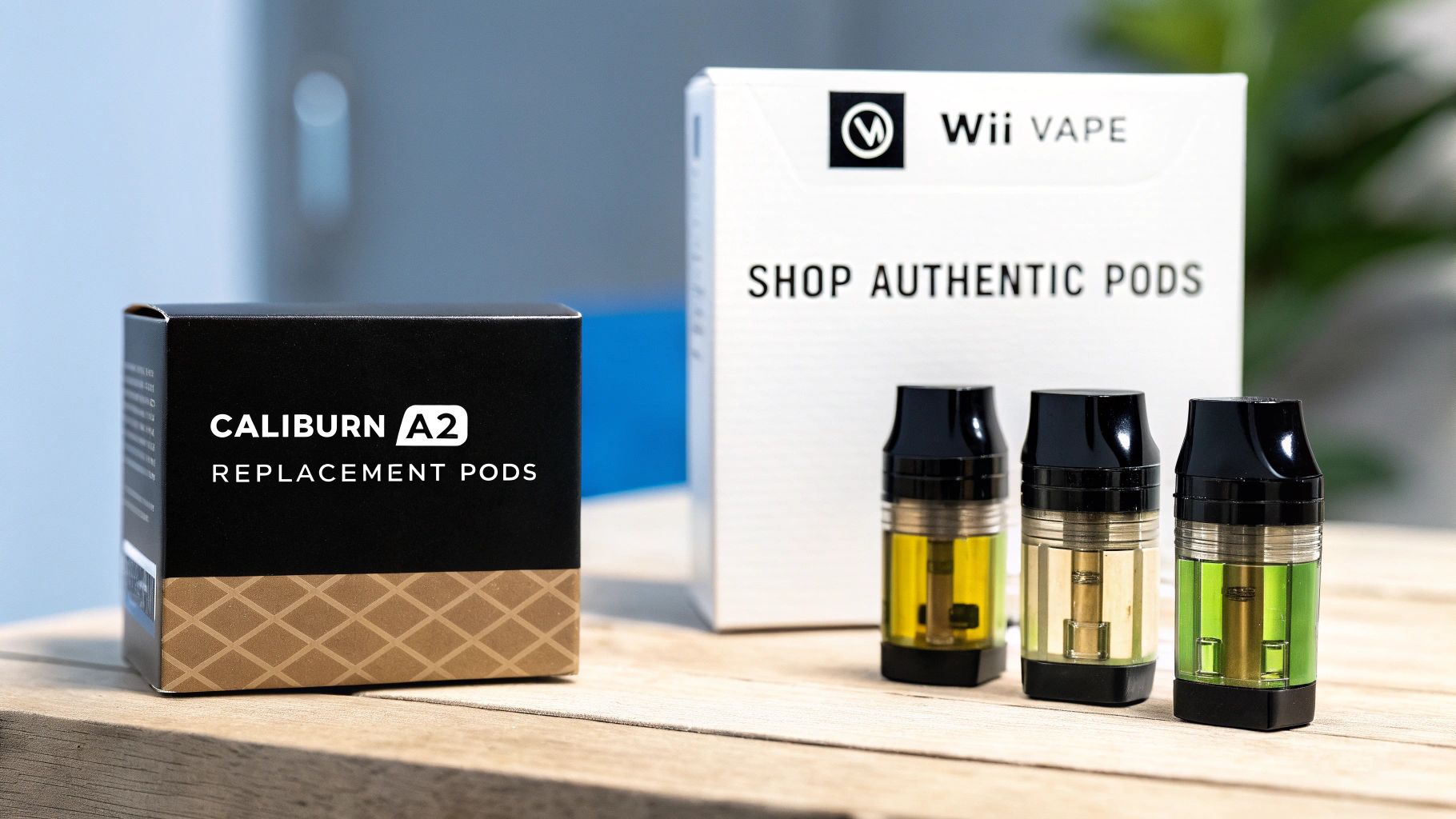 Black Caliburn A2 replacement pods box, white Wii Vape box, and three colorful vape pods on wood.