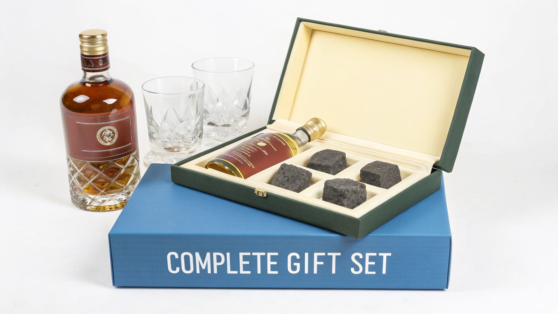 A complete scotch whisky gift set featuring a large bottle, two glasses, a smaller bottle, and four chilling stones.