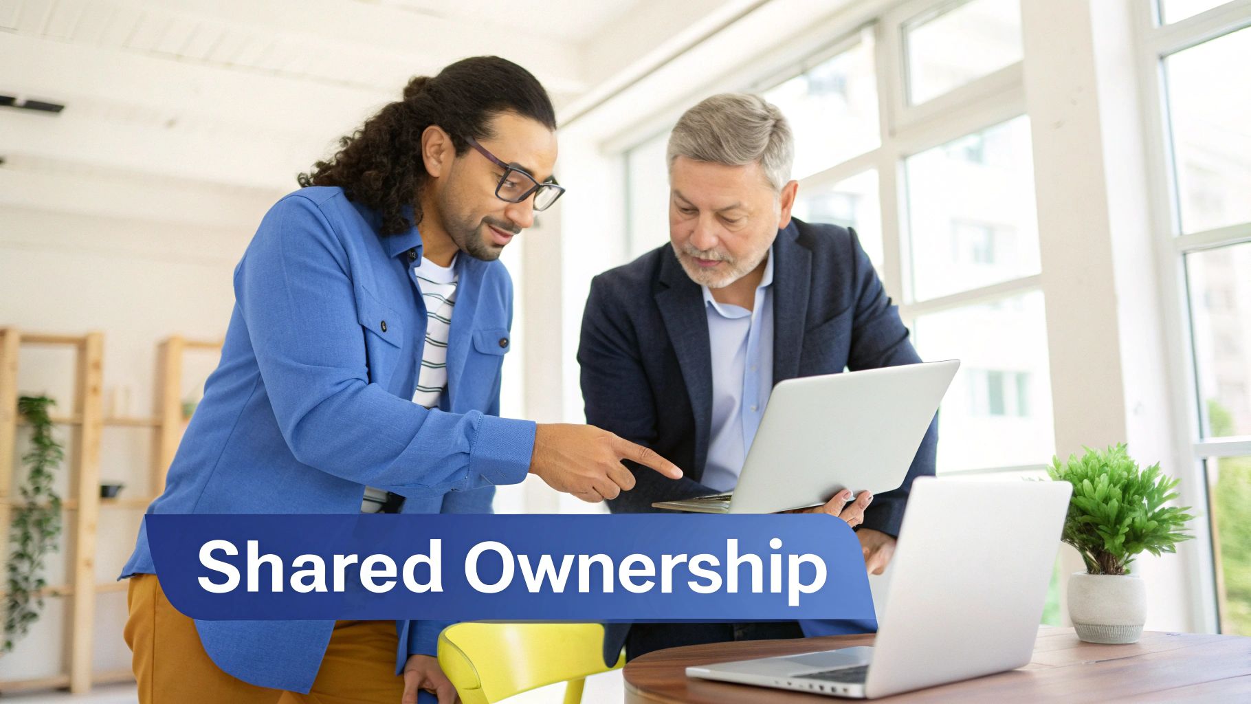Two diverse business professionals collaborating on a laptop, demonstrating shared ownership in a bright office.