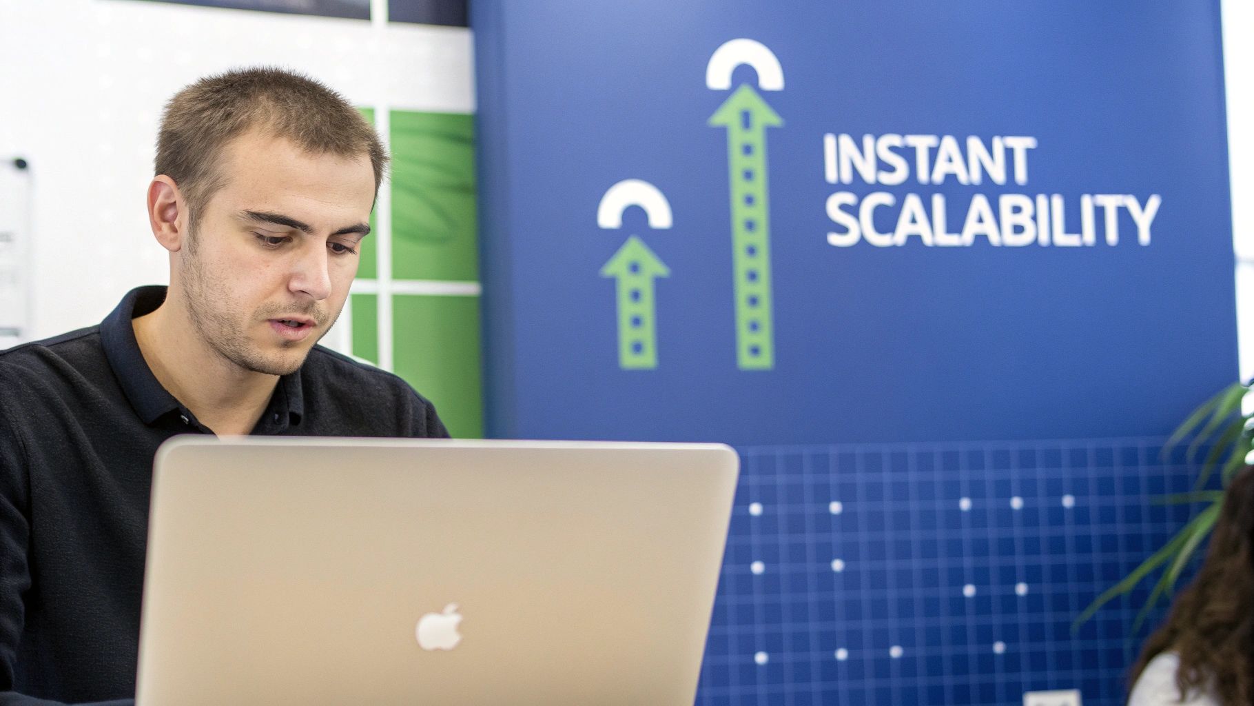 A focused man works on a MacBook laptop, with a blue banner showcasing 'Instant Scalability' and growth arrows behind him.